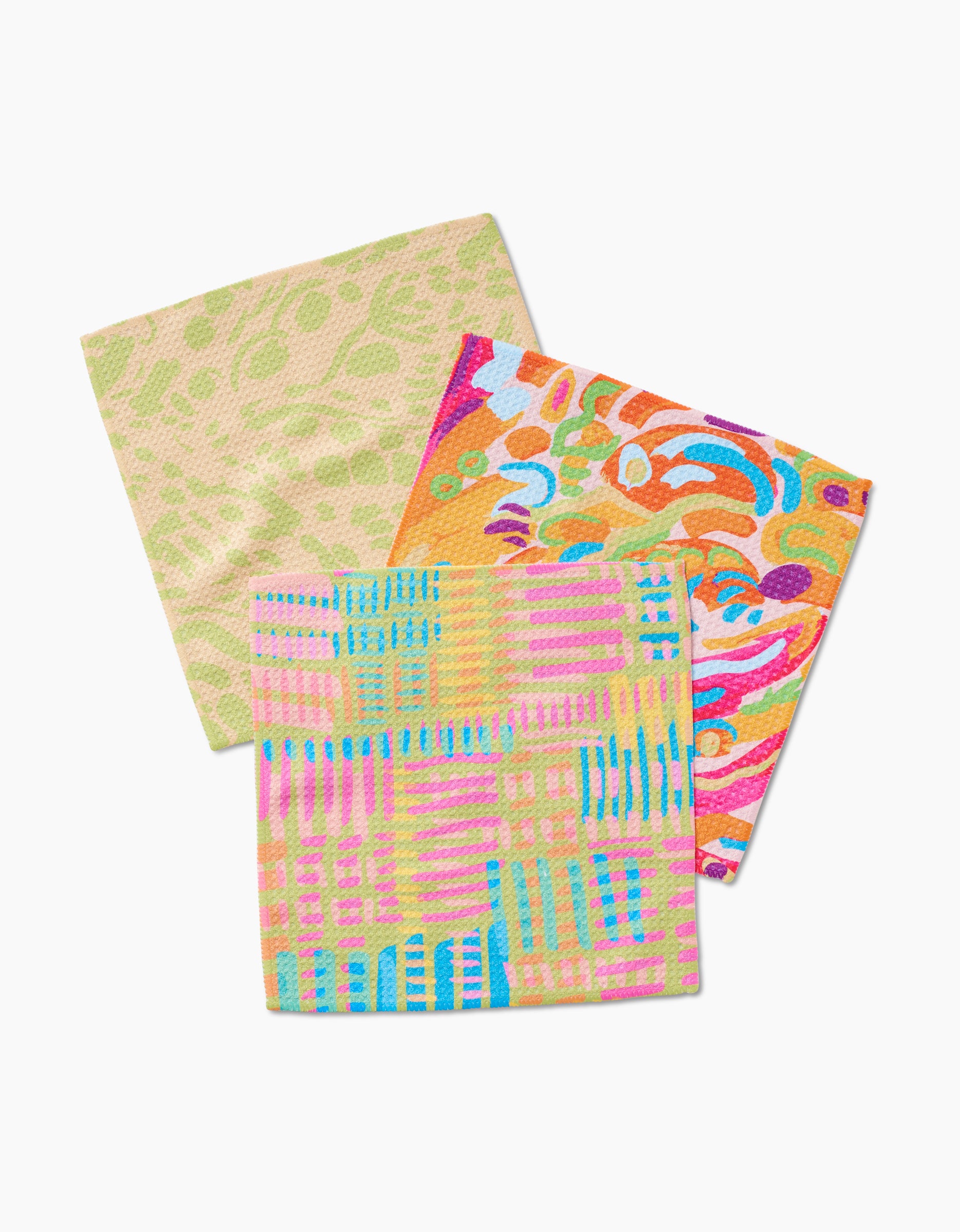 Three vibrant Positive Vibes dishcloths by Sareka Unique are stacked: one with a beige animal print, one with a multicolored abstract swirl, and one in a pastel geometric grid—all made from durable Geoweave fabric.