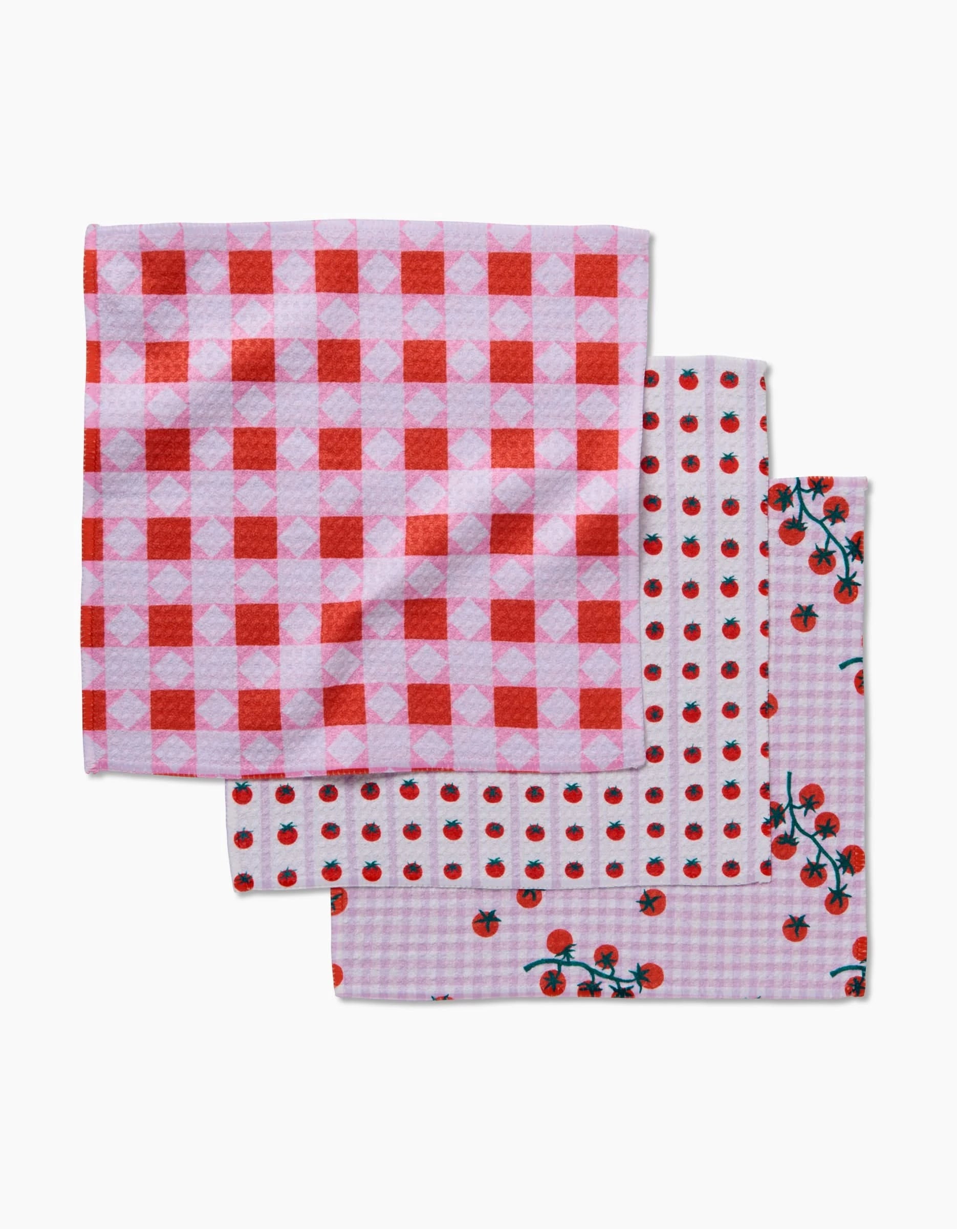 Quilt Tomato Harvest by Brittany Jepsen: set of three folded dishcloths made from recycled materials—red and pink checkered, red dots on white, and cherry tomatoes with vines on a light purple checkered background.