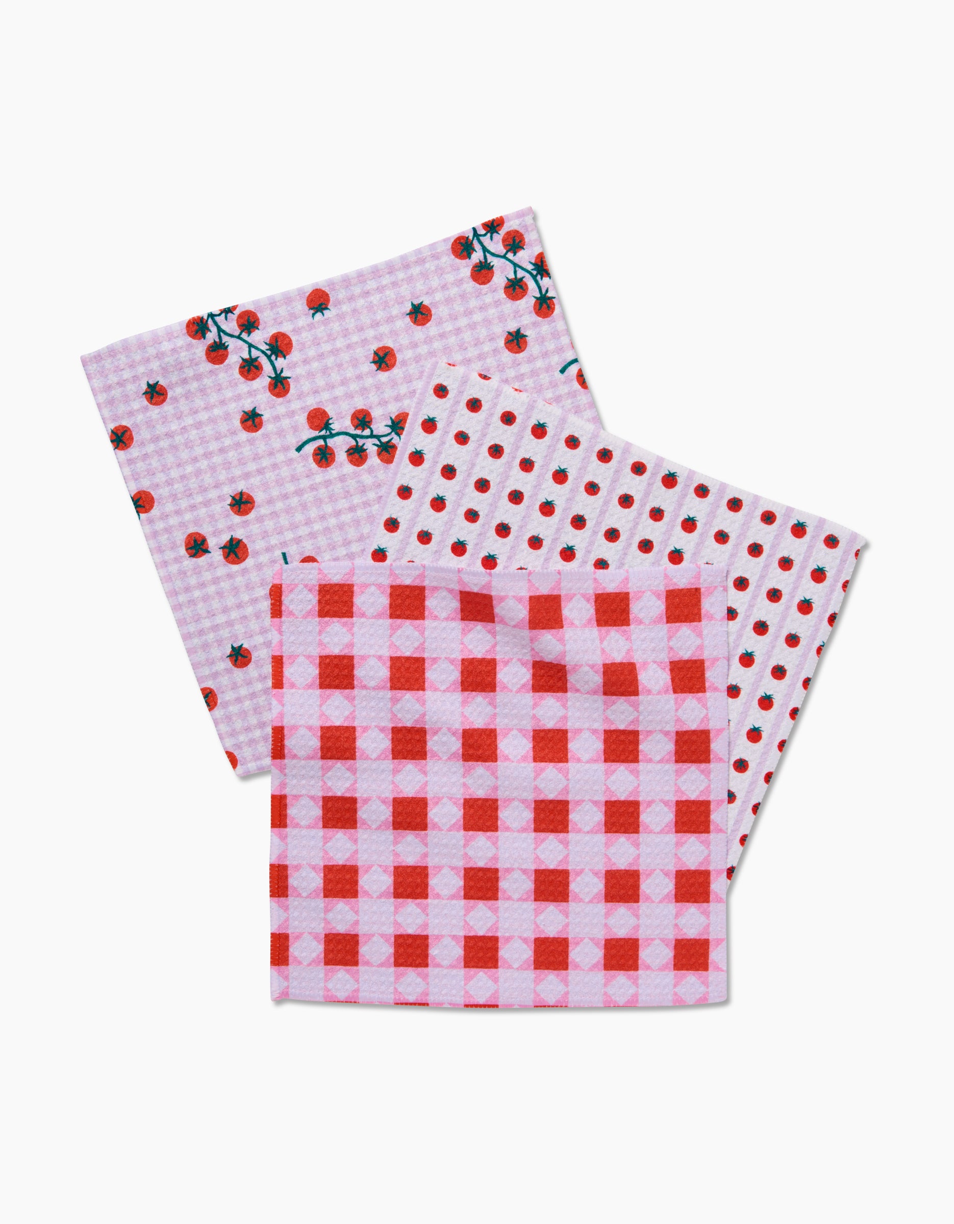 The Quilt Tomato Harvest dishcloth set by Brittany Jepsen features three soft Geoweave cloths: one with cherry prints, another with red polka dots, and a third in red and pink gingham.