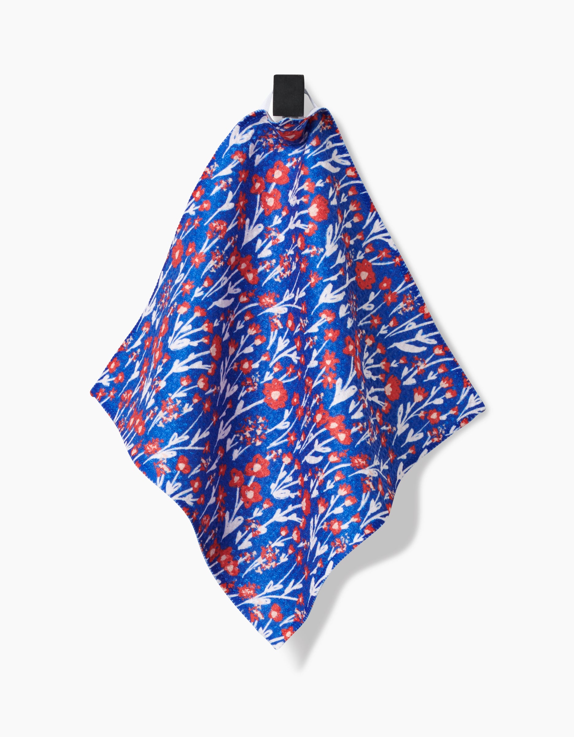 The Royal Garden handkerchief by Danelys Sidron, made from recycled materials, features a blue fabric with a vivid red and white floral pattern and hangs from a black loop against a plain white background.