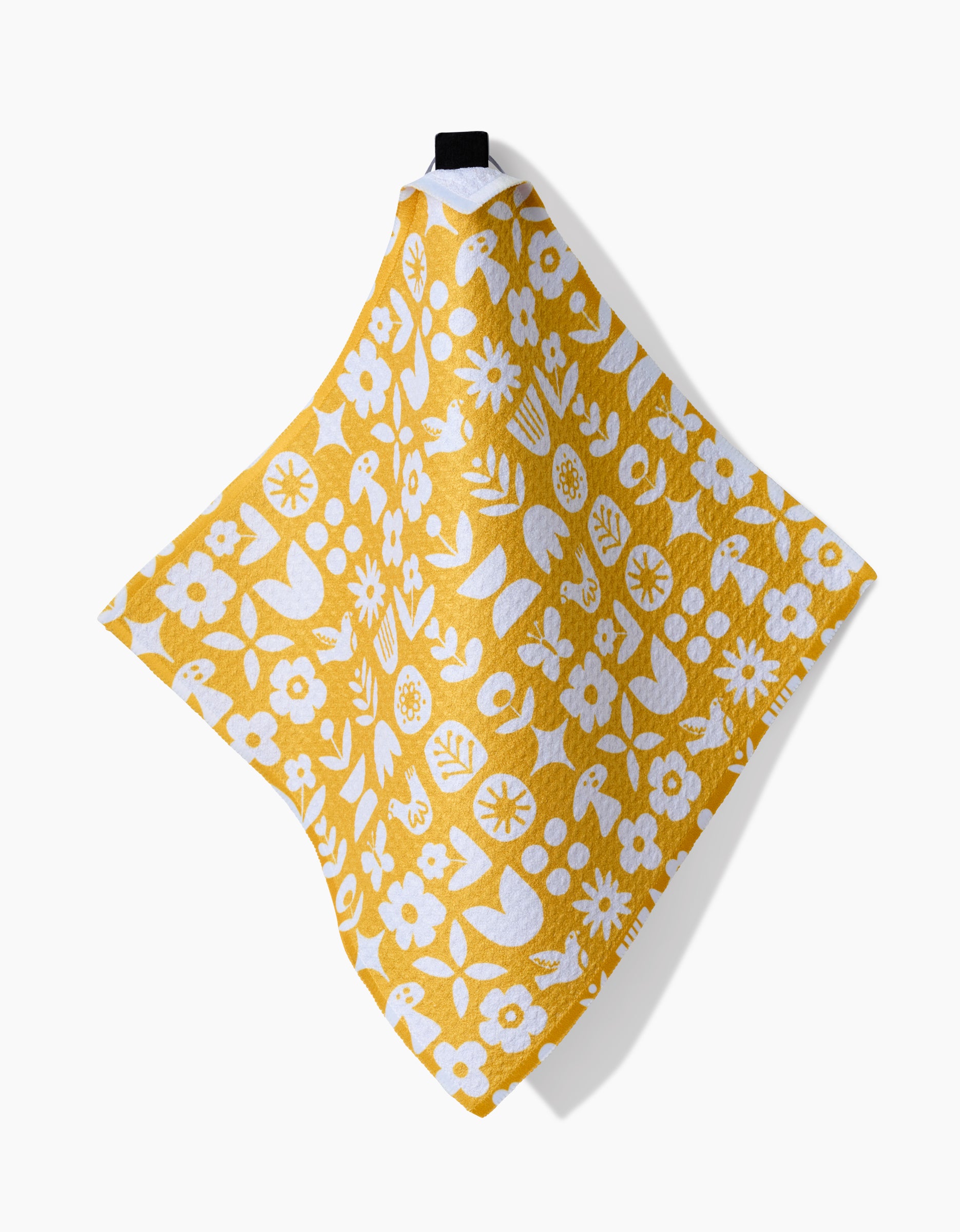 The Kayla Ann Scandi Spring dishcloth features yellow Geoweave fabric with white floral, bird, and watering can designs. Super-absorbent, it hangs from a black loop at the top and is shown against a white background.