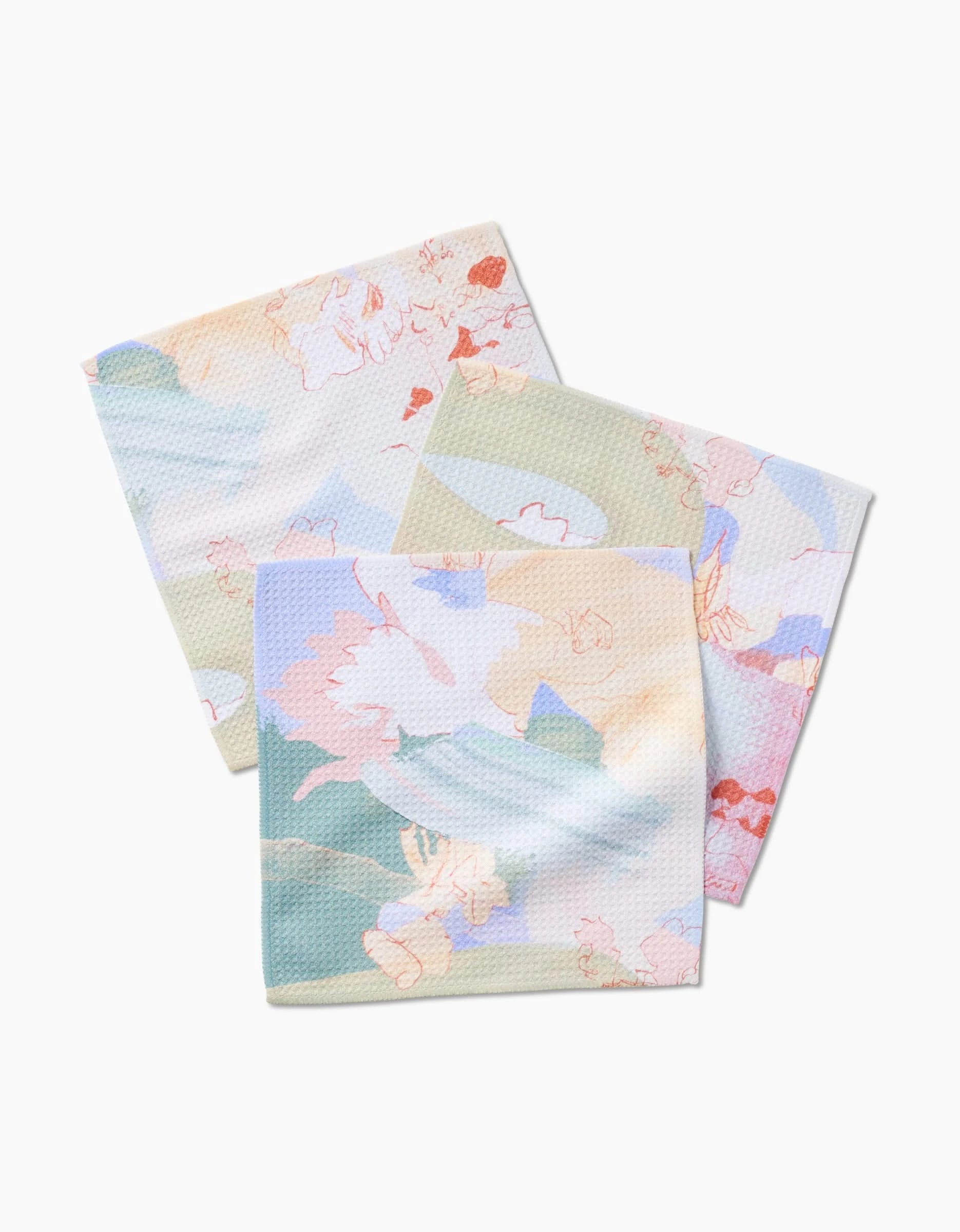 Three Secret Fort cloth napkins by Kristina Baker, made from recycled materials, feature a soft pastel abstract floral pattern and are displayed slightly overlapping on a white background.