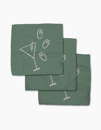 Three green Shaken Not Stirred cocktail napkins by Rosa Kichline, made from recycled materials, feature a white line martini glass and three olives design, arranged in a slightly overlapping stack on a white background.