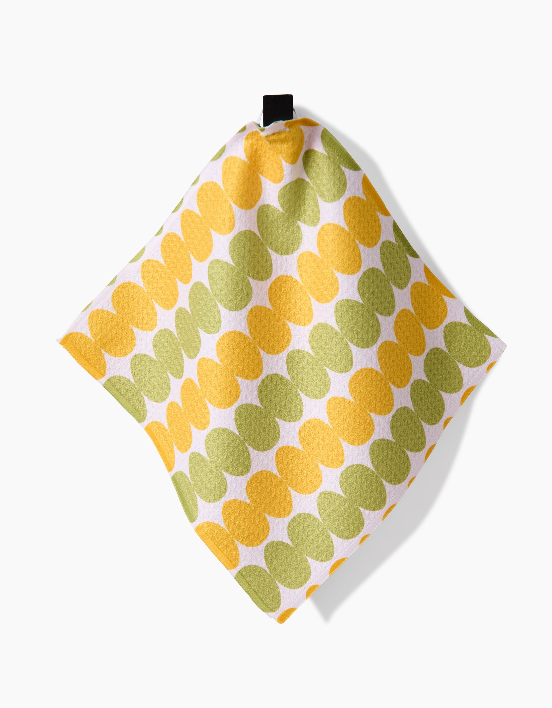 The Kayla Ann Signs of Springtime square dish towel, made from recycled materials, showcases yellow and green overlapping ovals on a white background and hangs from a black fabric loop.