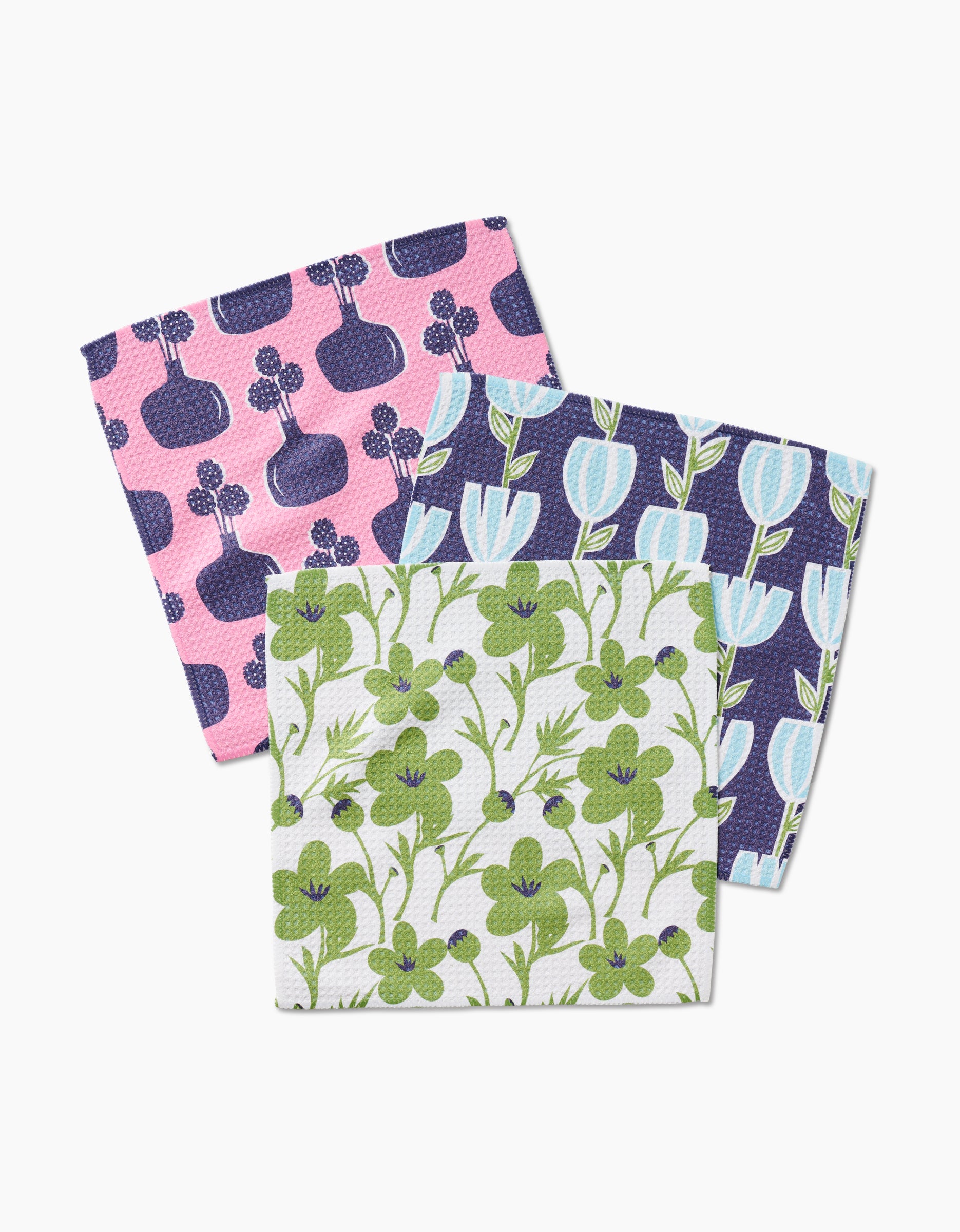 The Lizzie Clark Spring Bouquet set includes three colorful Geoweave fabric cloth napkins: one with pink and purple vases, one with blue tulips on dark, and one super-absorbent napkin with green leaves and berries on white.