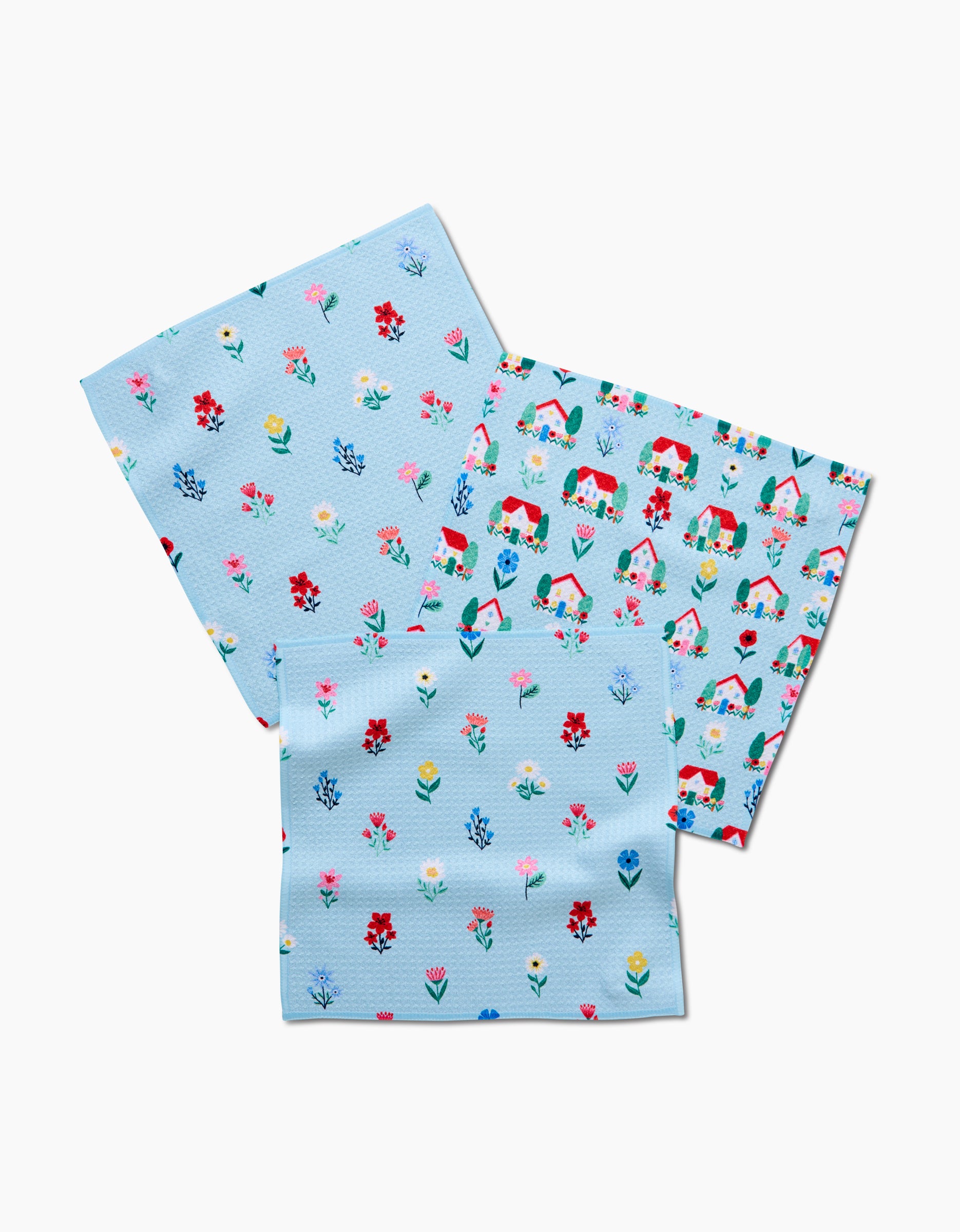 The Ceyda Alasar Spring House Blossom Dishcloth Set includes three light blue Geoweave cloths featuring small illustrated flowers, leaves, and plants on a white background with colorful, garden-inspired designs.