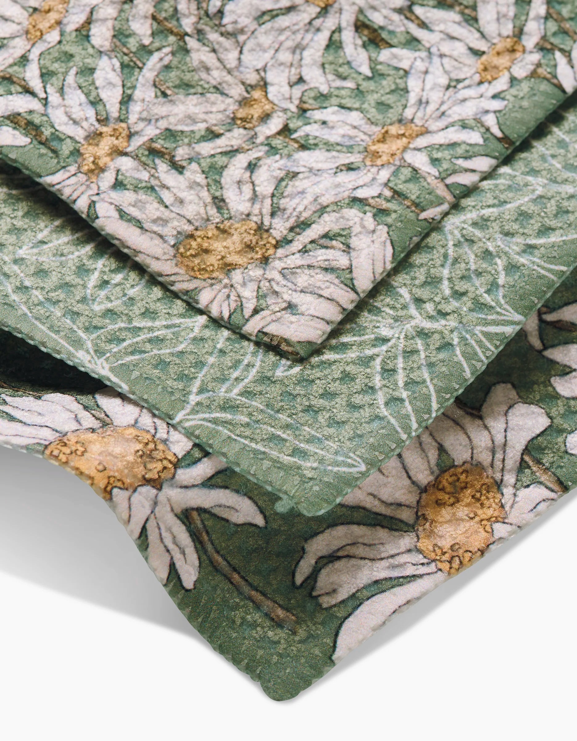 Close-up of Aubrey Fairchilds Springtime dishcloth set in textured green, featuring stacked white daisies with yellow centers.