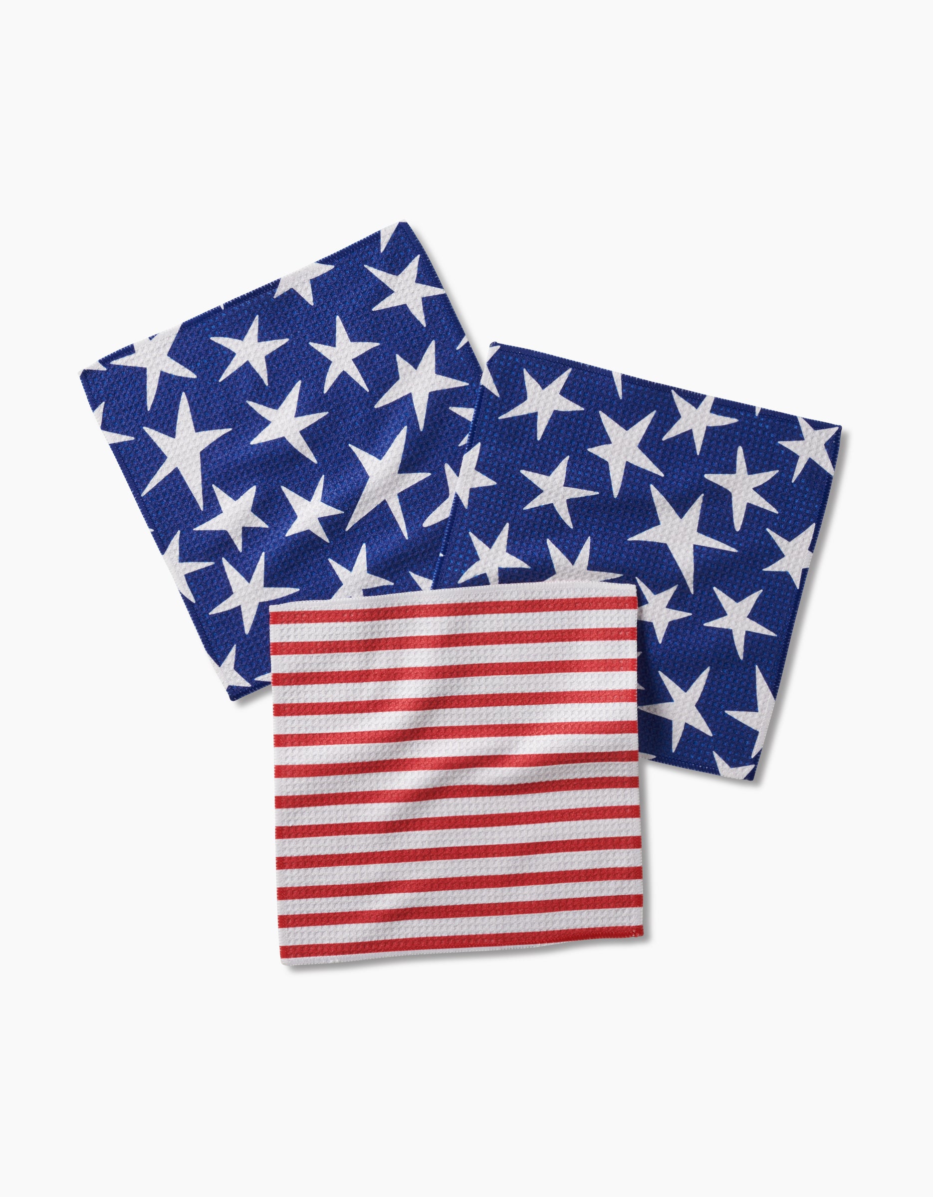 The Mindfulnice Stars And Stripes set features three recycled cloth napkins—two blue with white stars and one red with white stripes—arranged on a white background for a stylish look.