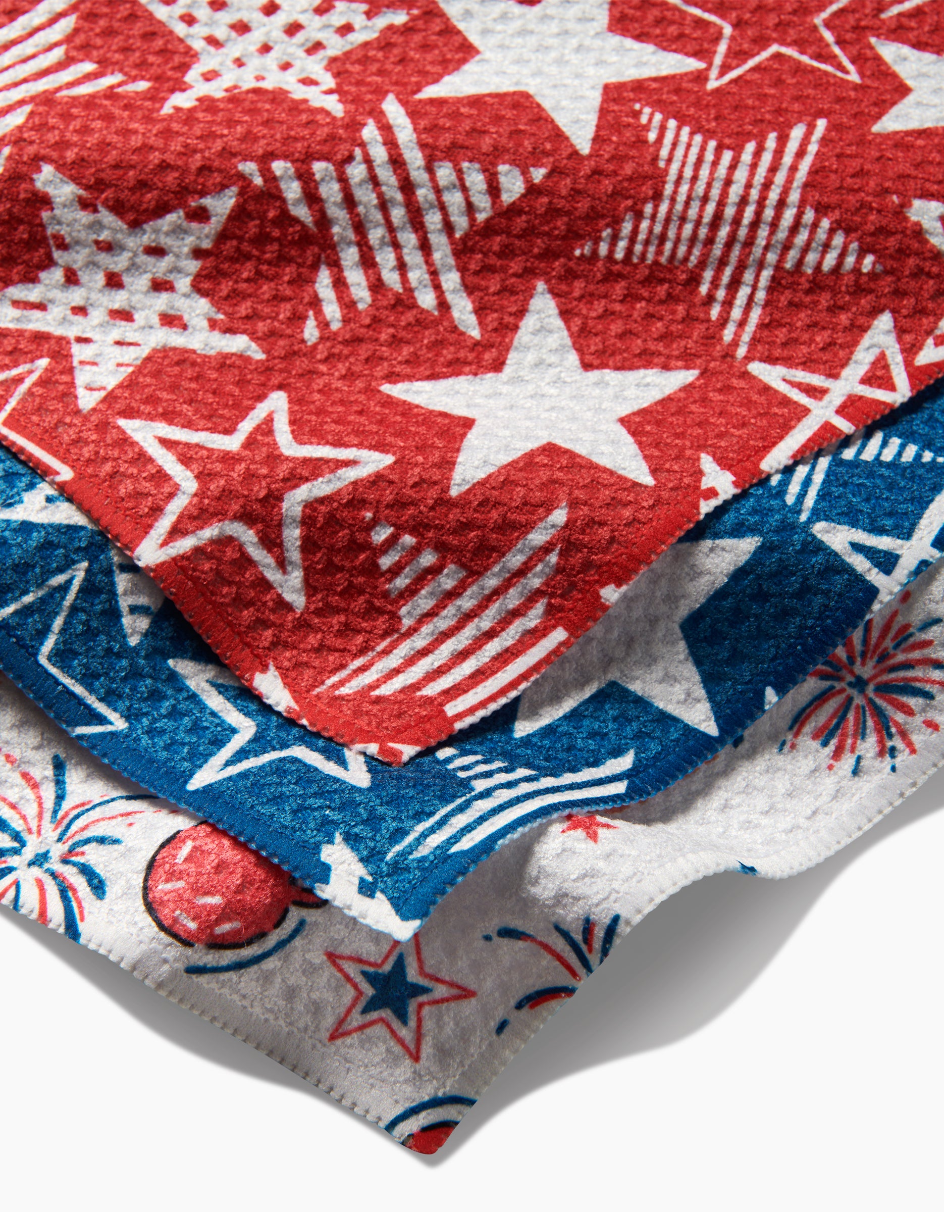 Three textured fabrics from Hufton Studios Stars In Your Eyes collection, featuring red, white, and blue star and firework patterns, evoke festive Americana—crafted from recycled materials for an eco-friendly touch.