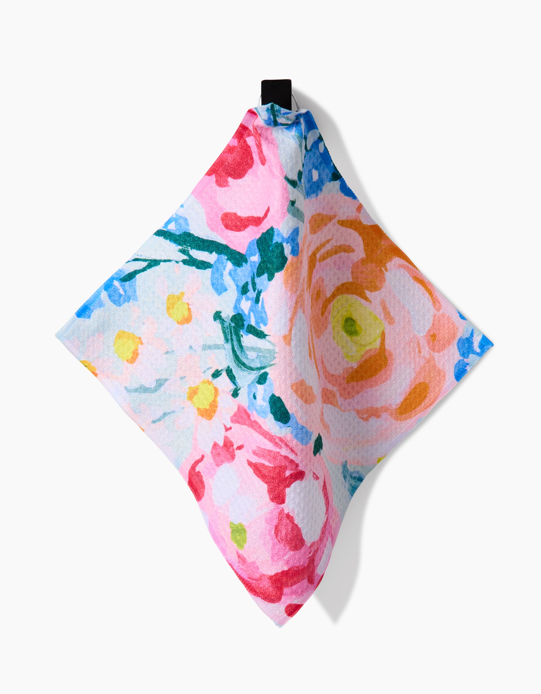 The Suzzy dish towel by Ania Zwara Art features a vibrant floral print in pink, orange, yellow, blue, and green on white Geoweave fabric. It hangs from a small black loop at the top.
