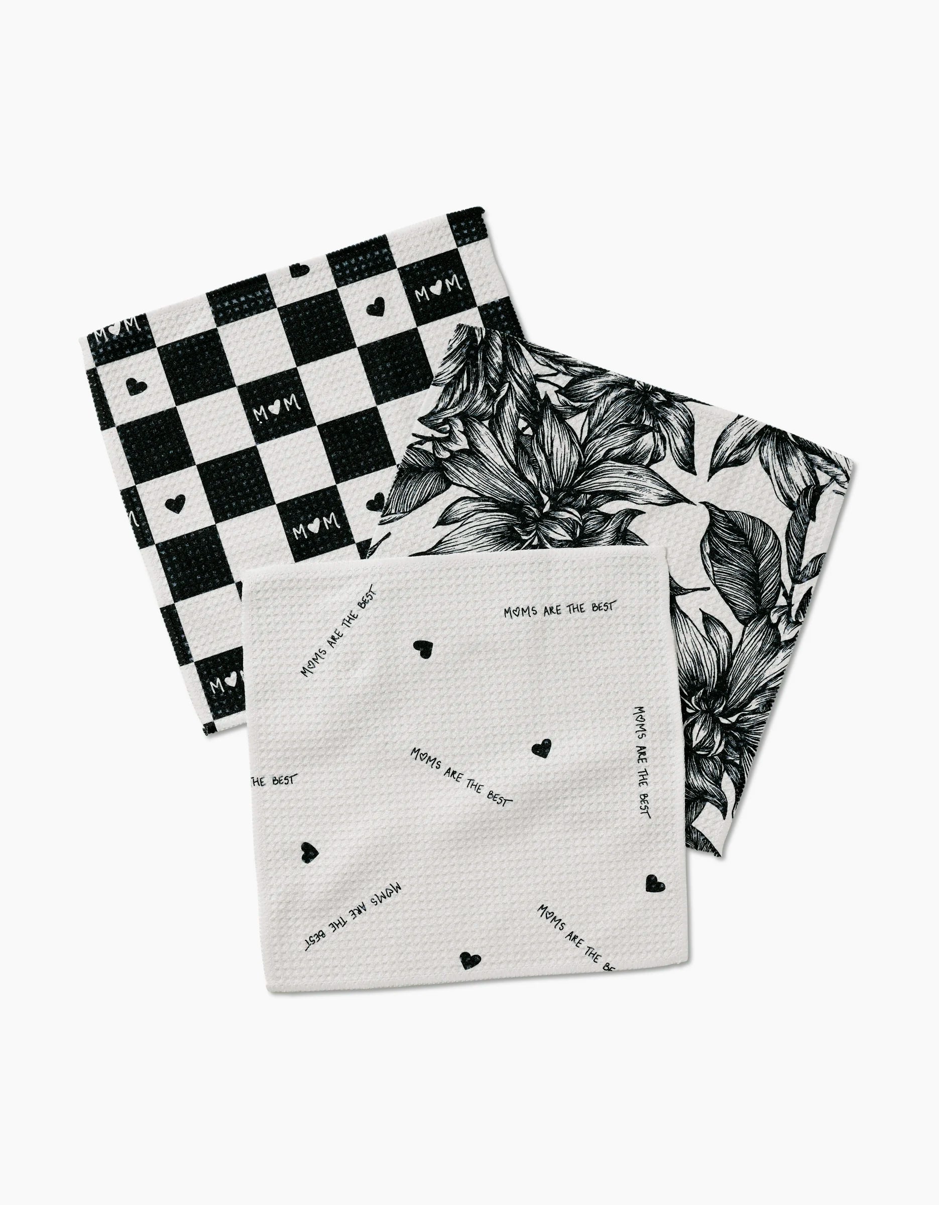 The Best Dishcloth Set by GEOMETRY features three square cloths: black & white buffalo check with hearts, bold black florals, and white with MOMS ARE THE BEST text—made from recycled materials for eco-friendliness.