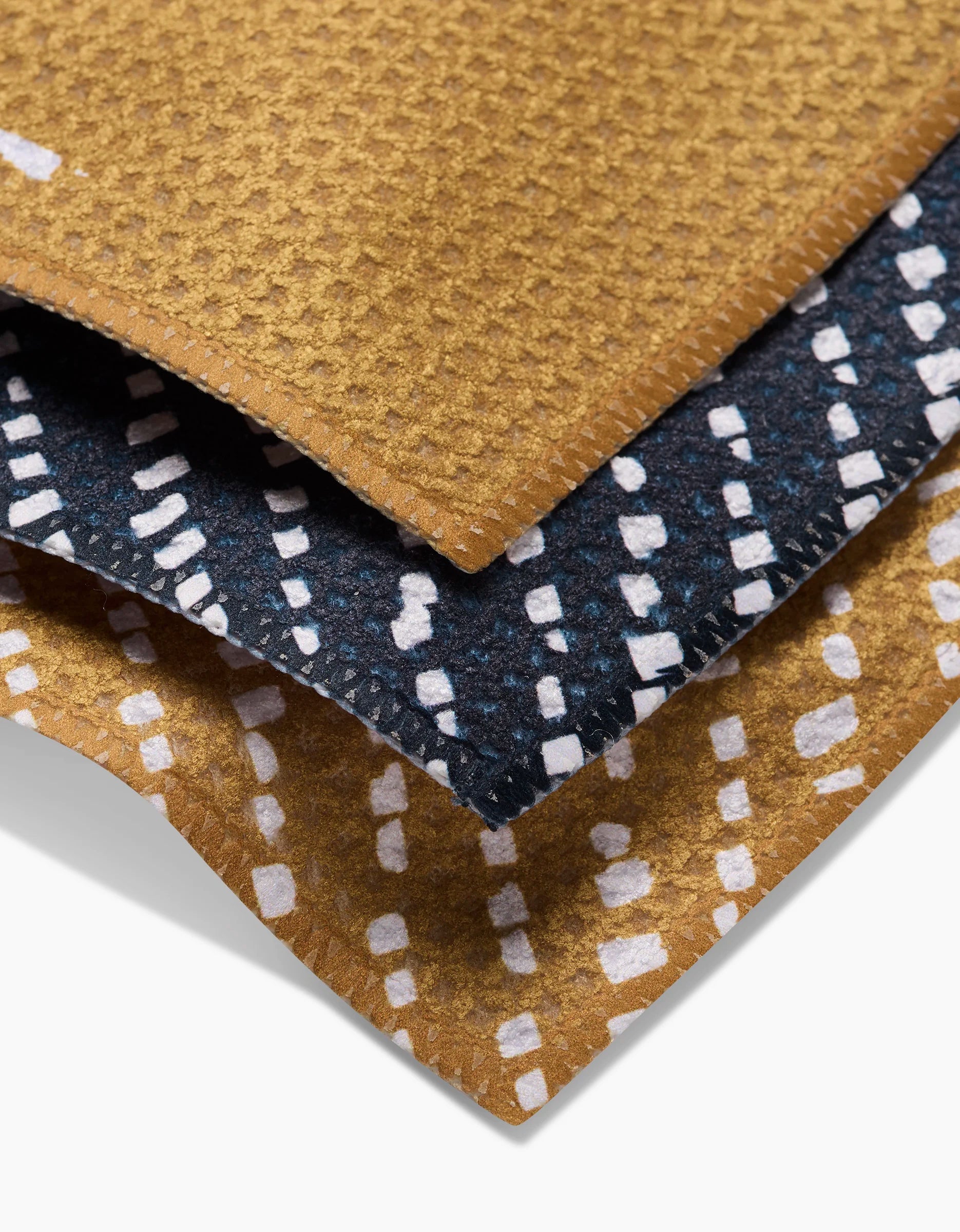 The GEOMETRY This And That dishcloth features three layers of textured Geoweave fabric: golden brown with white dots on top and bottom, and dark blue with white dots in the middle—stylish, absorbent, and perfect for your kitchen.
