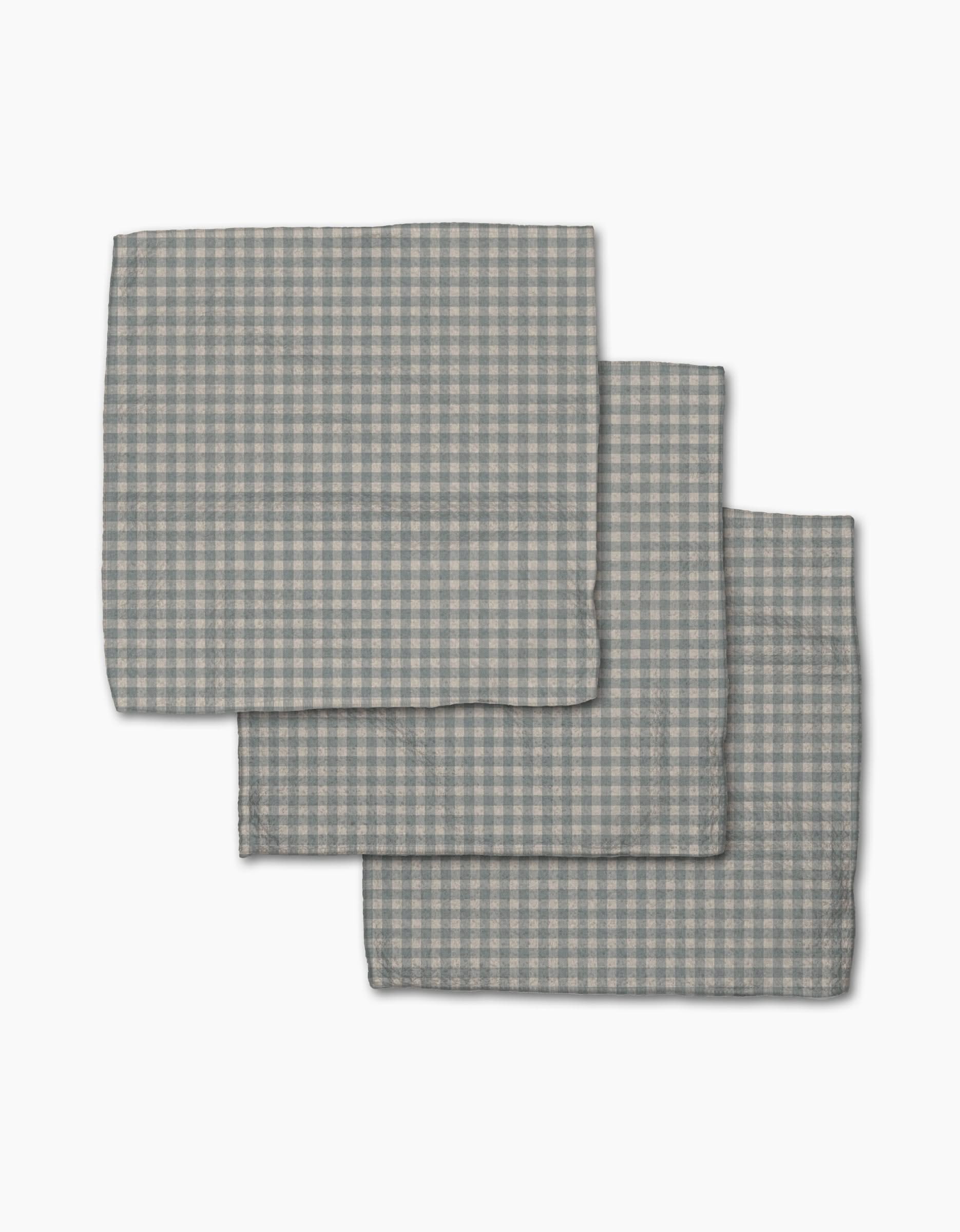 Three folded Tidepool Check napkins by Jenny Keller, featuring a gray and white gingham pattern, are stacked on a white background—ideal as stylish recycled dishcloths or a dishcloth set for your kitchen.