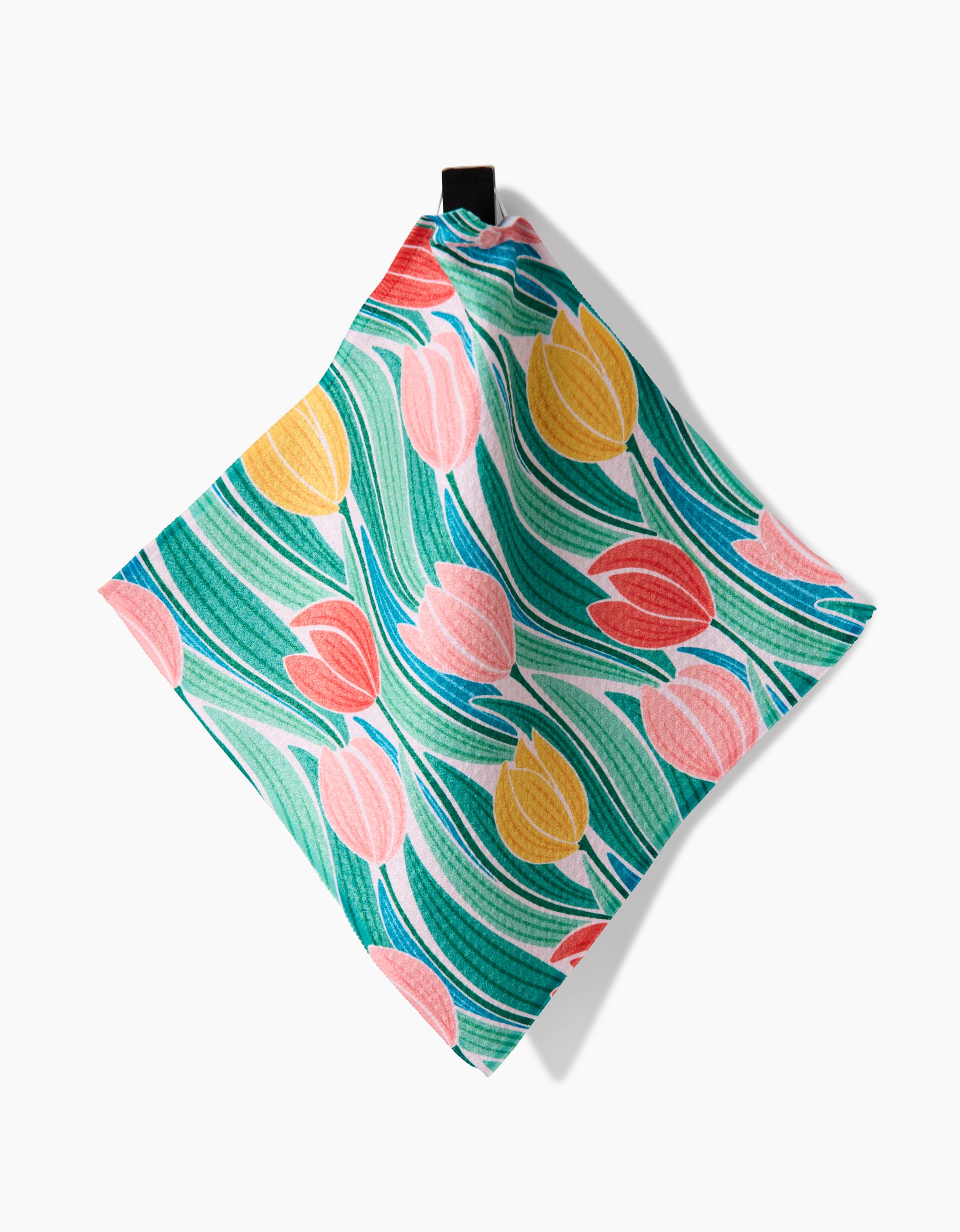 The Tranquil Tulips cloth napkin by Sarah Daugherty is made from recycled materials and features red, yellow, and pink tulips on a green leafy background, shown here against a white surface.