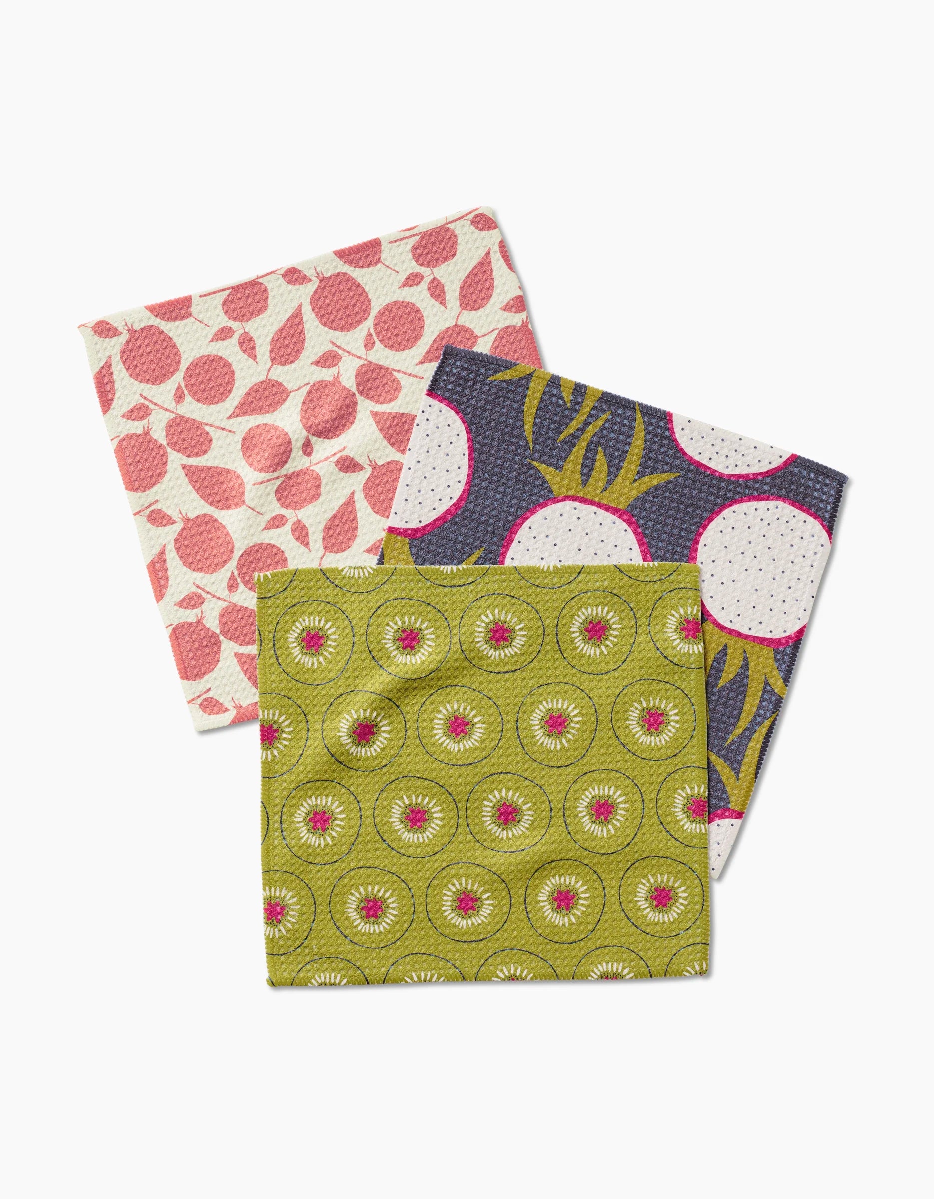 Three Lizzie Clark Tropical Fruit cloth napkins—super-absorbent Geoweave fabric—feature pink with white circles, blue and yellow with dots, and green with pink and white floral designs stacked together.