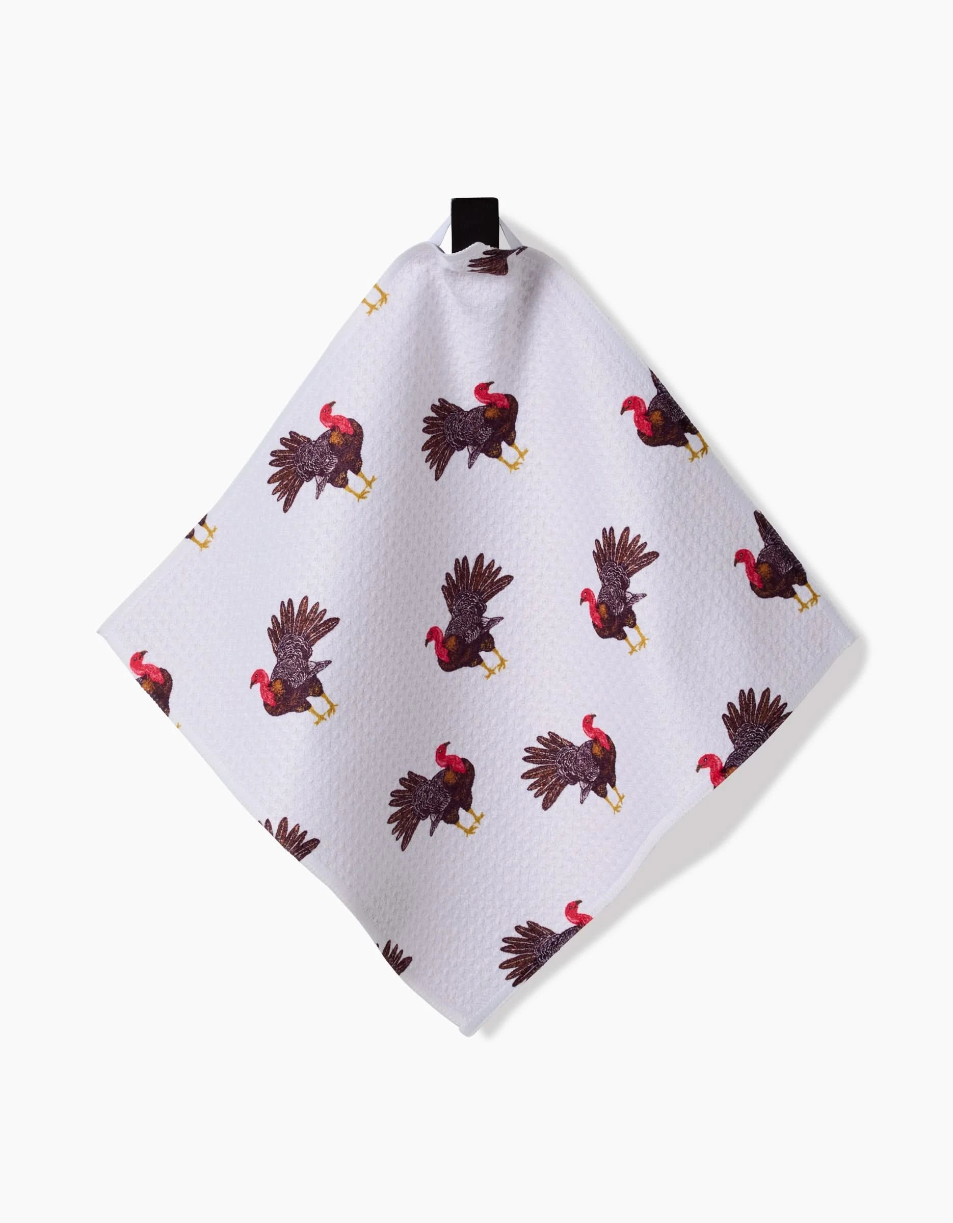 The Turkey Day Parade towel by Vaishali Design Studio is a white recycled cloth with a pattern of illustrated turkeys in various poses, hanging by a black loop against a white background.