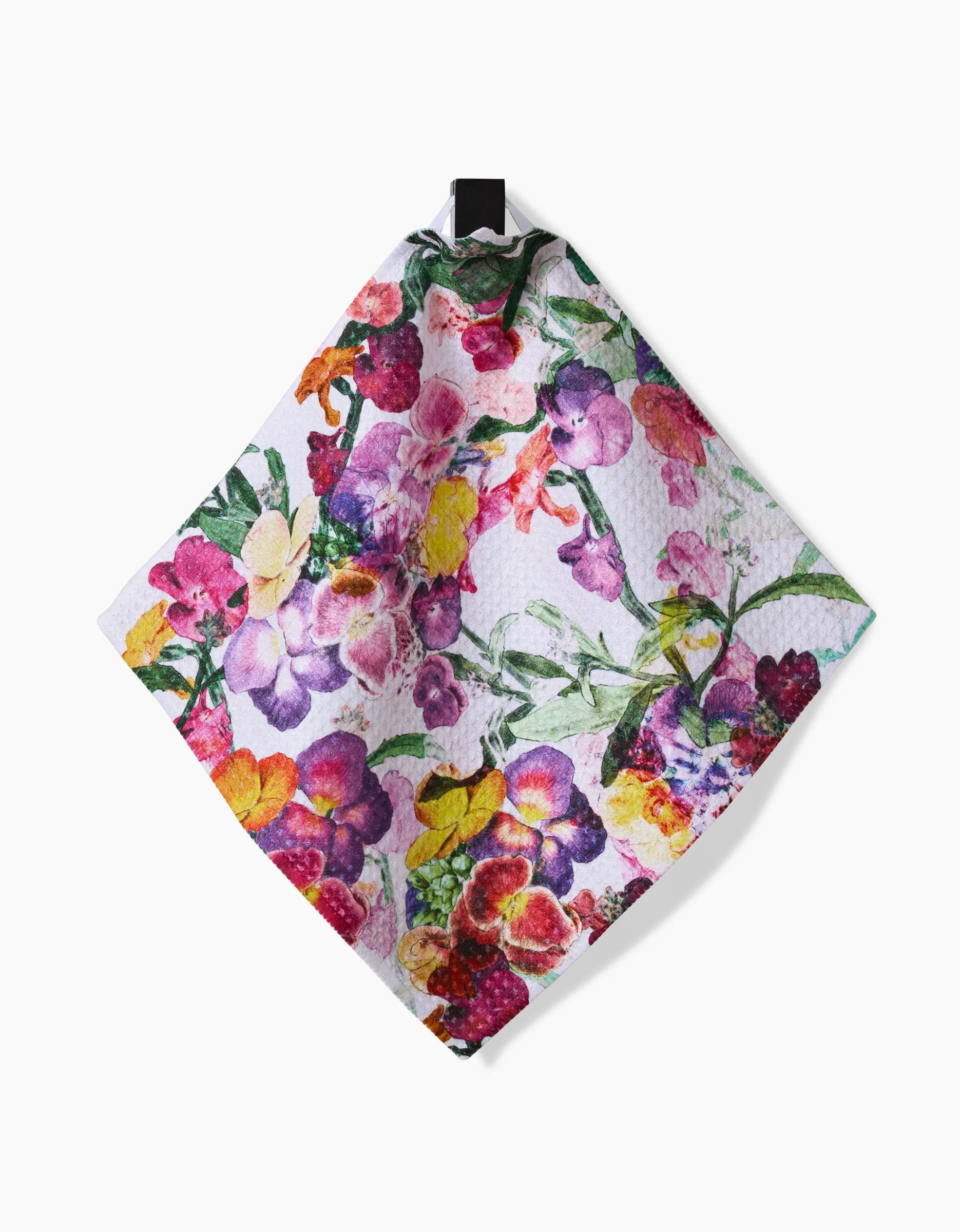 The Wallflower kitchen towel by Pascale Dilger features a vibrant pink, purple, yellow, and green floral pattern on Geoweave fabric and hangs from a black loop against a white background.