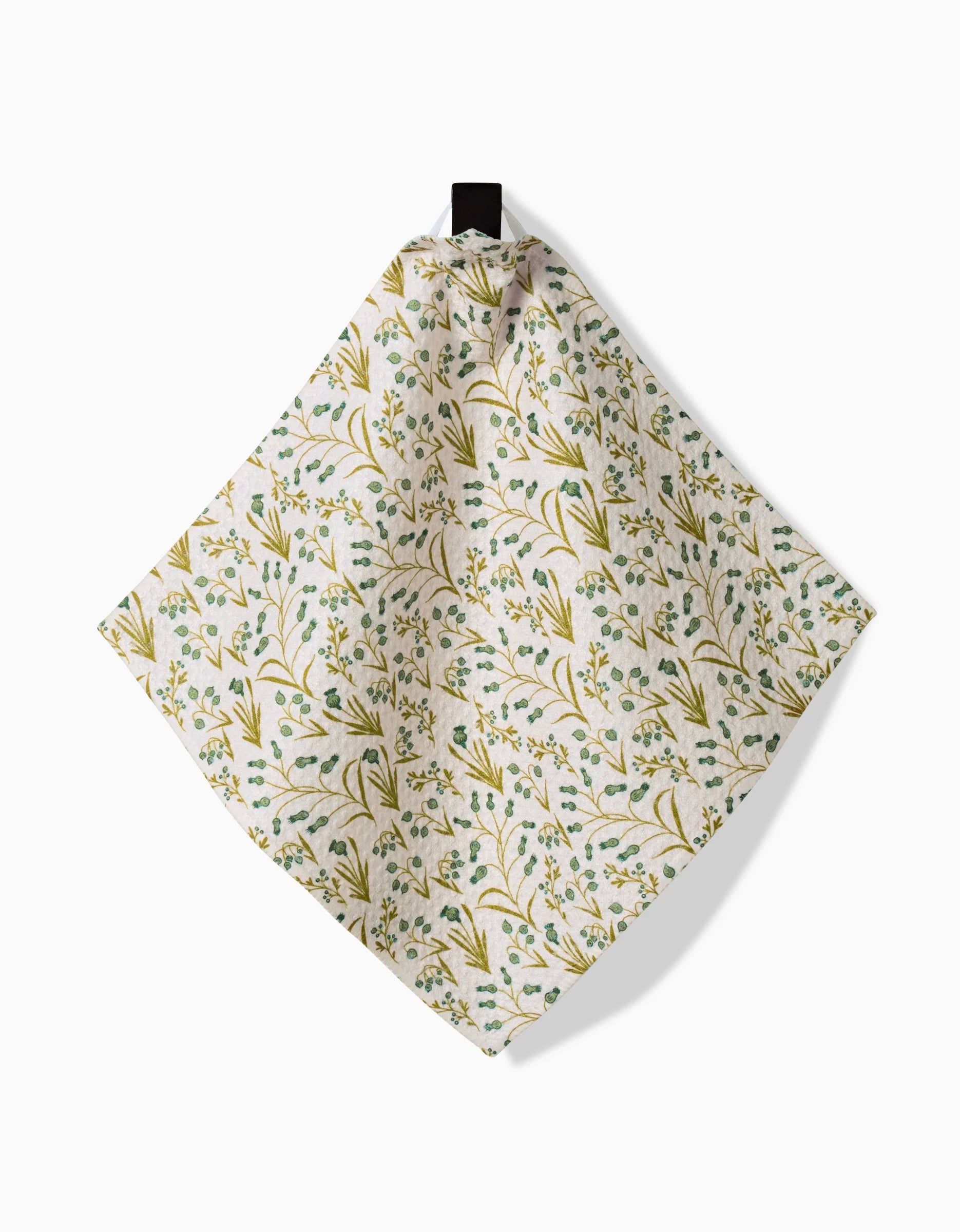 The Wildlight square dishcloth by Danelys Sidron, featuring a green and yellow floral pattern and made from recycled materials, hangs from a black hook against a white background.