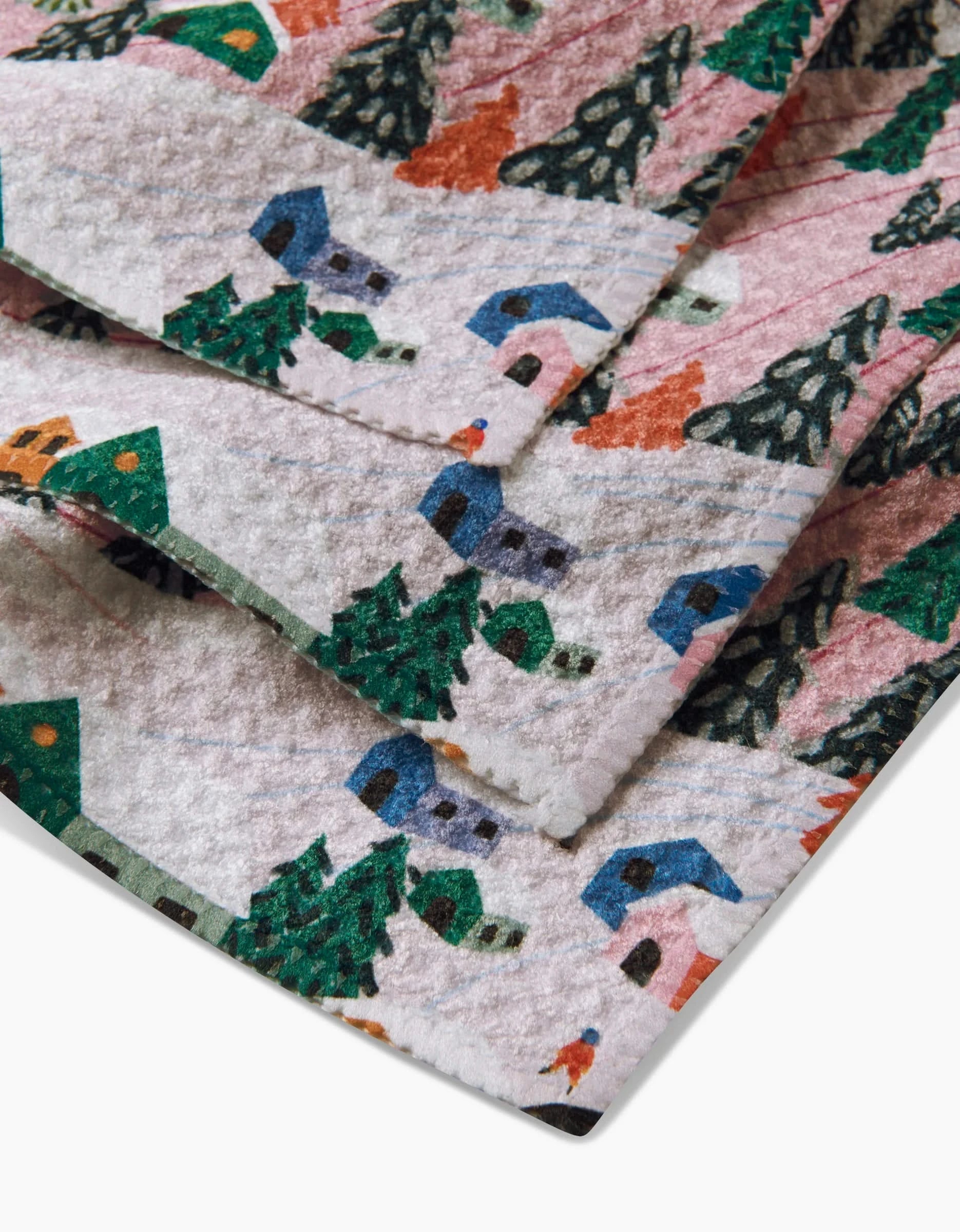 A close-up of Ceyda Alasar’s Winter Holiday paper napkins, featuring a festive winter village scene with houses, pine trees, and snow. Made from recycled materials—perfect for eco-friendly celebrations.
