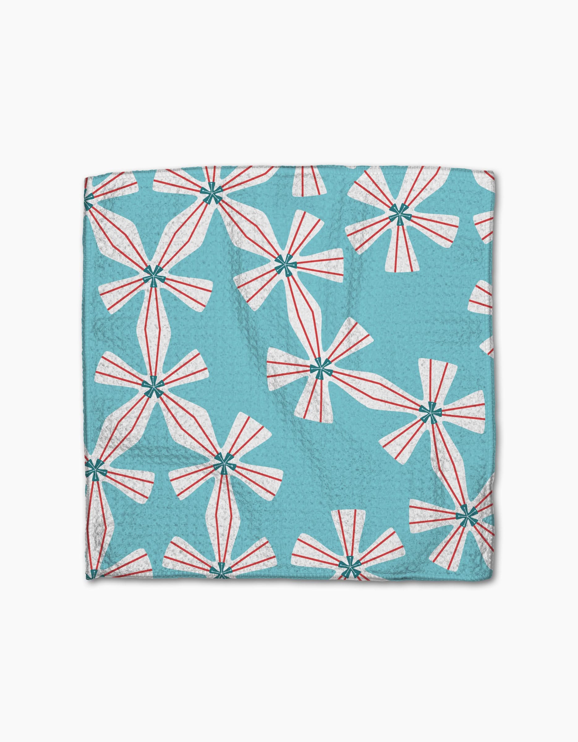 The Winter Holly quilt by Lizzie Clark is a folded blue cover made from recycled materials, featuring large white pinwheel flowers with red accents and green centers, displayed on a plain white background.