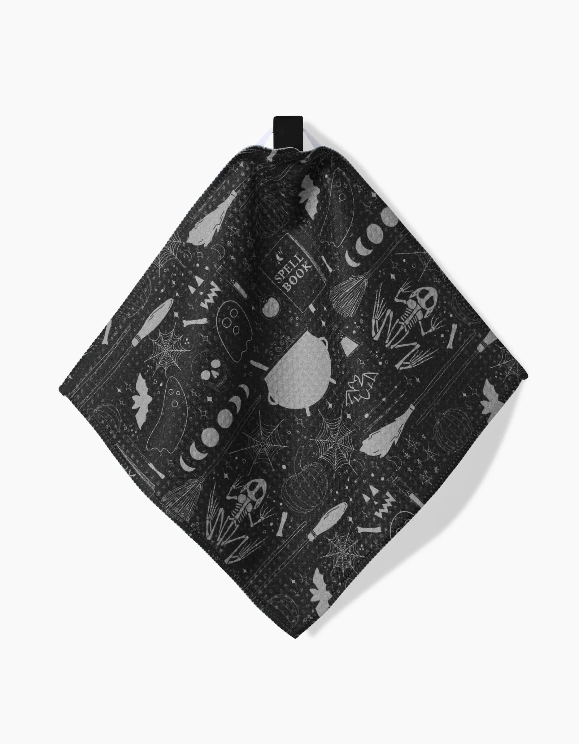 The Rosa Kichline Witches Brew dishcloth is made from black Geoweave fabric and features a Halloween pattern with ghosts, spiderwebs, bats, skeletons, a cauldron, spell book, and potion bottles. Super-absorbent and festive for cleaning.