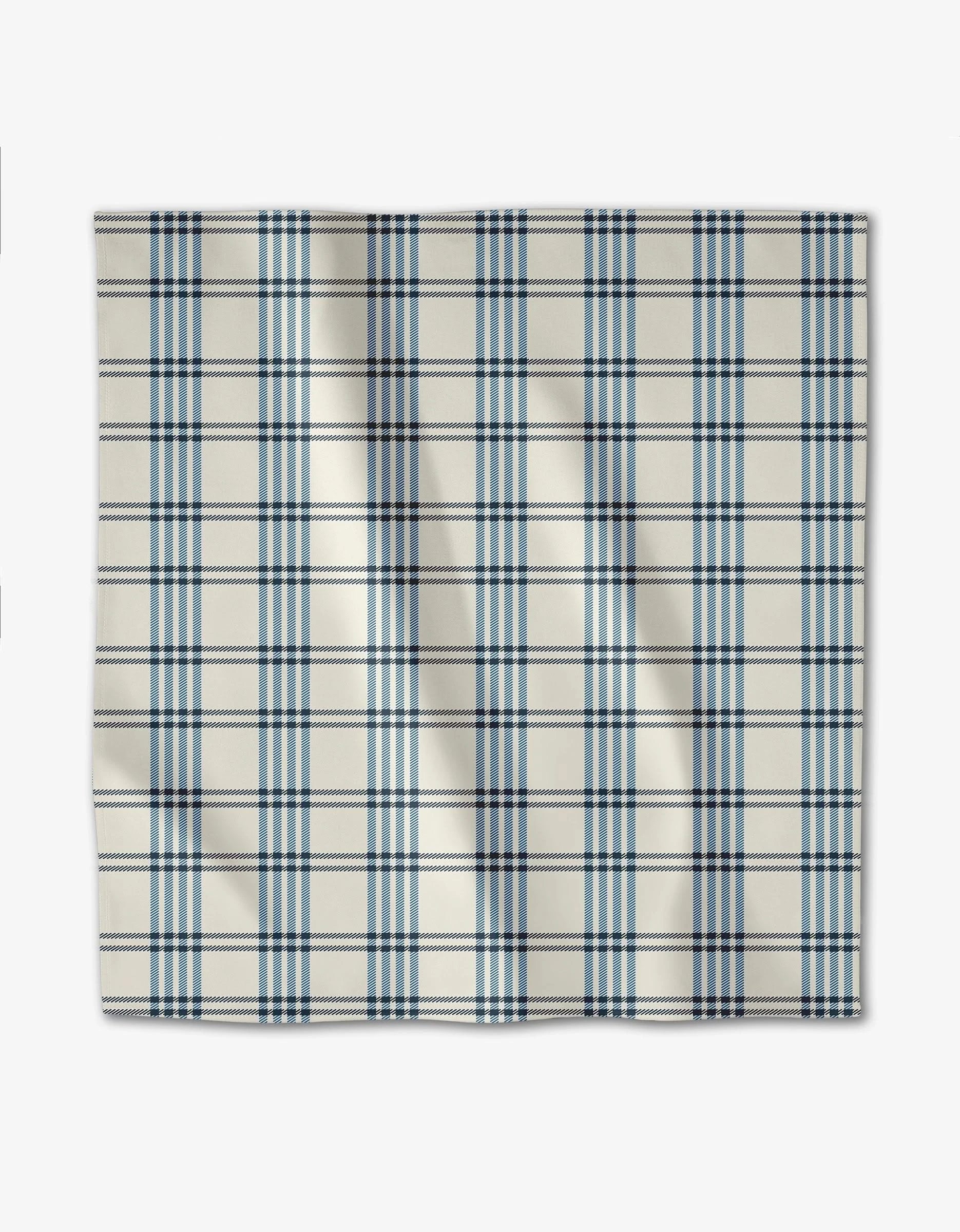 The Seafaring dinner napkin by GEOMETRY is a square, recycled Geosuede fabric in cream with a blue plaid pattern, featuring slight creases and laid flat on a white surface.