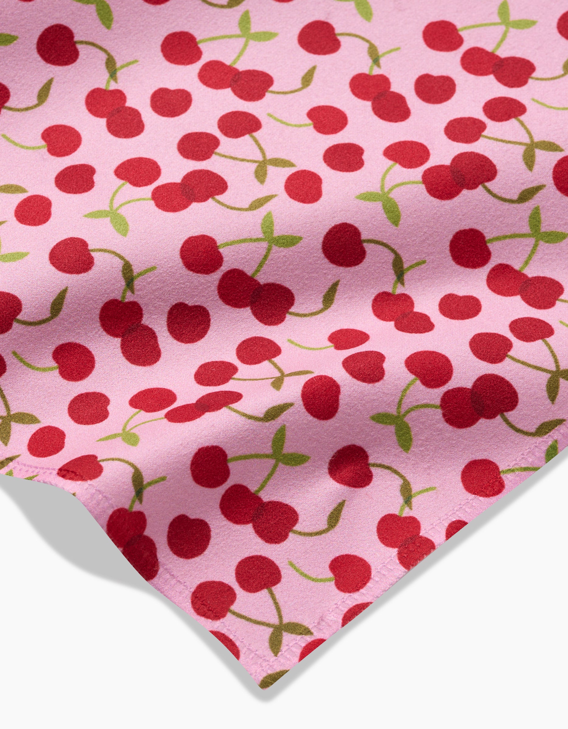 The Cheery Cherries dinner napkin set by GEOMETRY showcases a playful pink fabric with a vibrant cherry pattern and green stems, made from eco-friendly recycled materials—perfect for adding fun to your table.