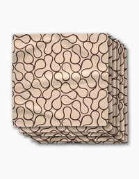 A set of four Gerdadzy Coffee Swirl dinner napkins in beige Geosuede fabric, each with a dark brown abstract line pattern, neatly stacked with slight overlap on a white background.