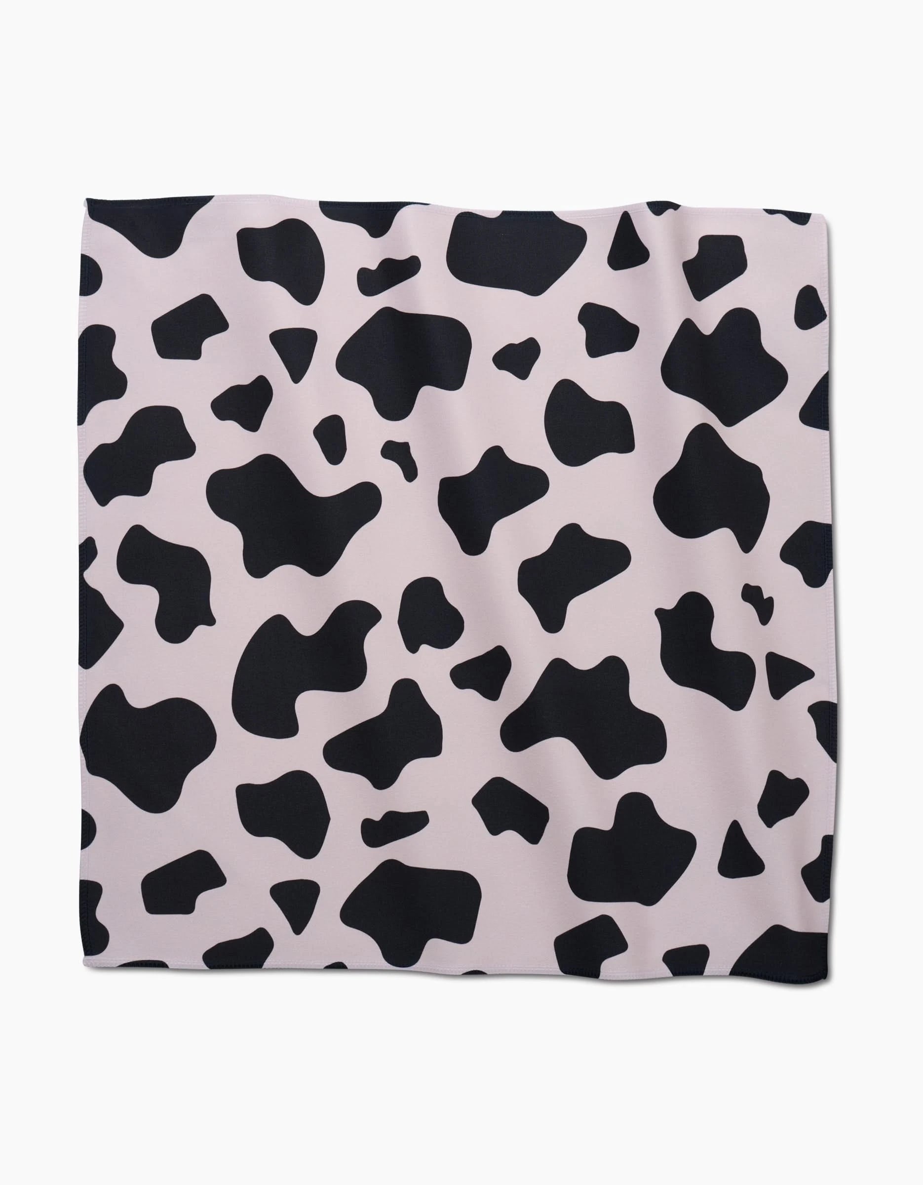 The GEOMETRY Cow Print Black Geosuede fabric features irregular black spots on a pale pink background, laid flat on white—an eco-friendly Dinner Napkin Set.