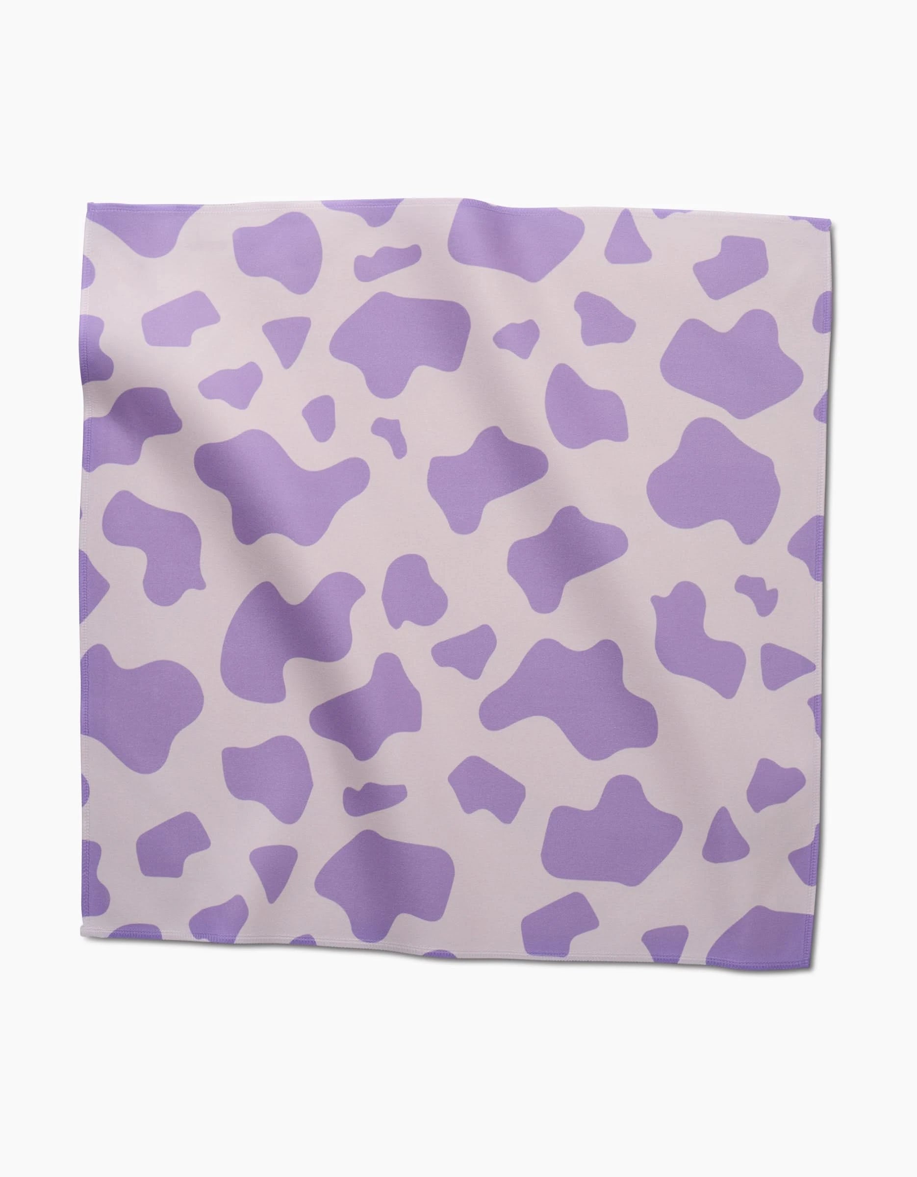 The GEOMETRY Cow Print Lilac is a square scarf with an abstract purple cow pattern on light beige, designed like chic, absorbent cloth napkins and shown flat on a white surface.