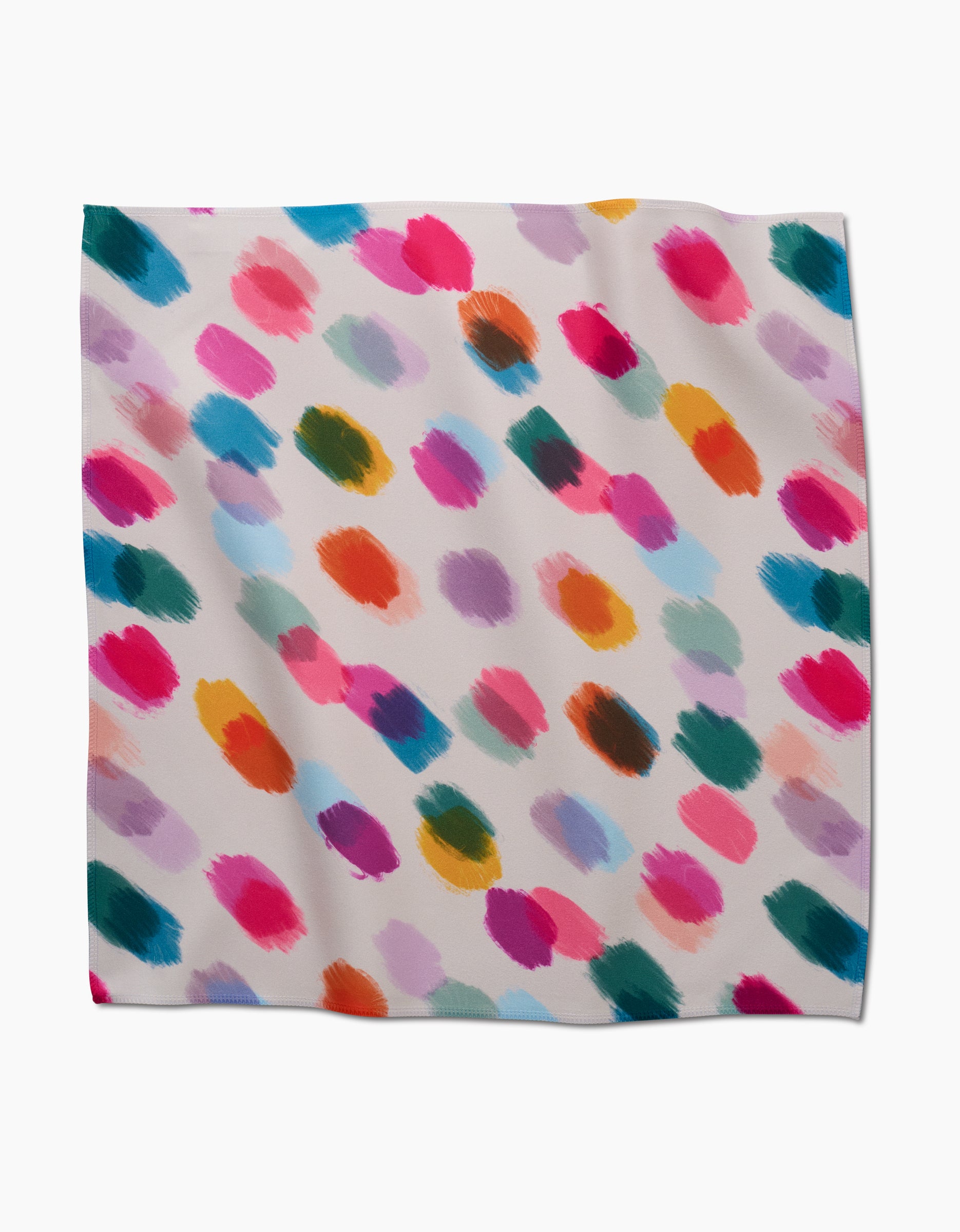 The Downpour dinner napkin by GEOMETRY features a white Geosuede fabric with diagonal brushstroke patterns in vibrant pink, blue, purple, green, orange, and yellow—crafted from recycled materials.