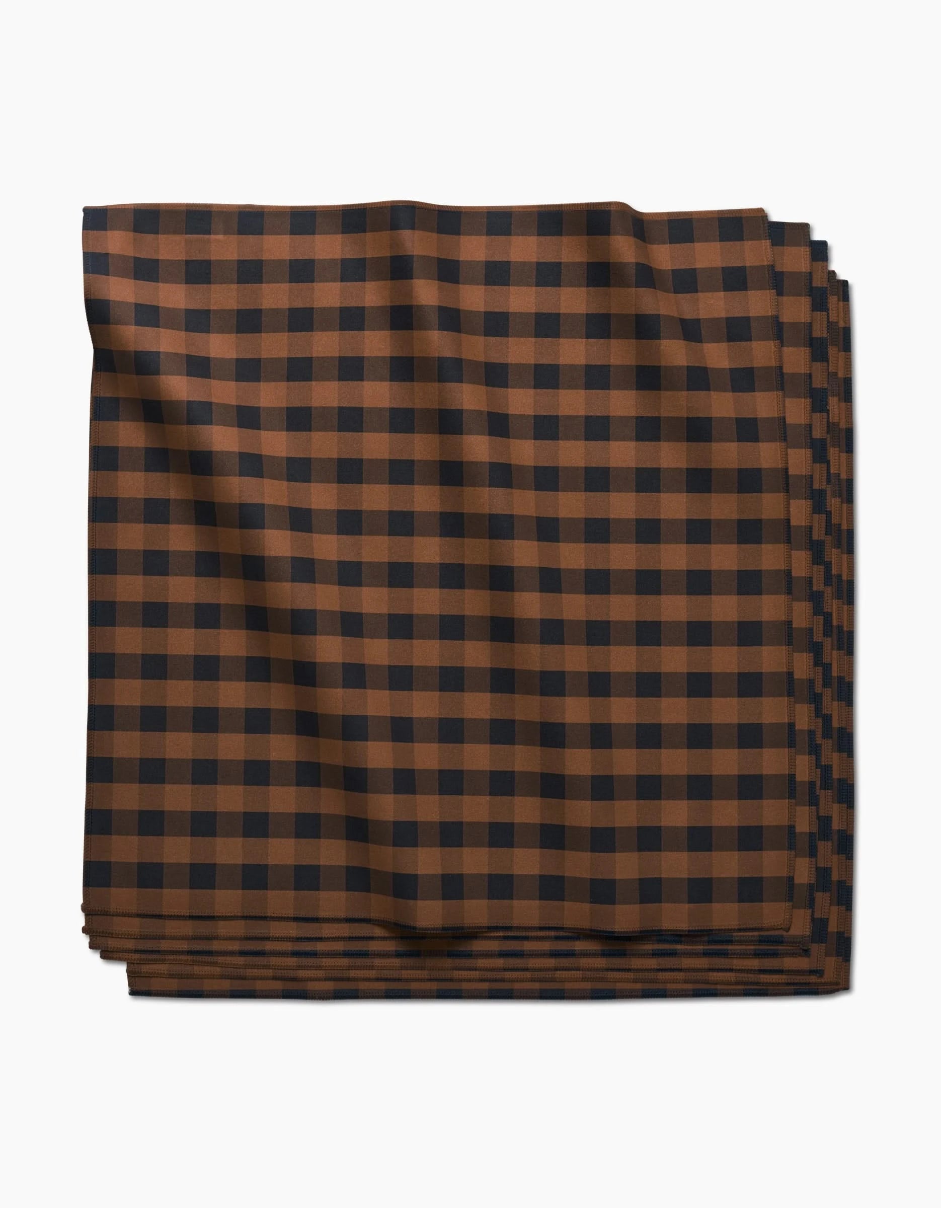 The Fall Gingham Dinner Napkin by GEOMETRY, crafted from Geosuede fabric, features a brown and black checkered pattern and is shown neatly folded against a white background.
