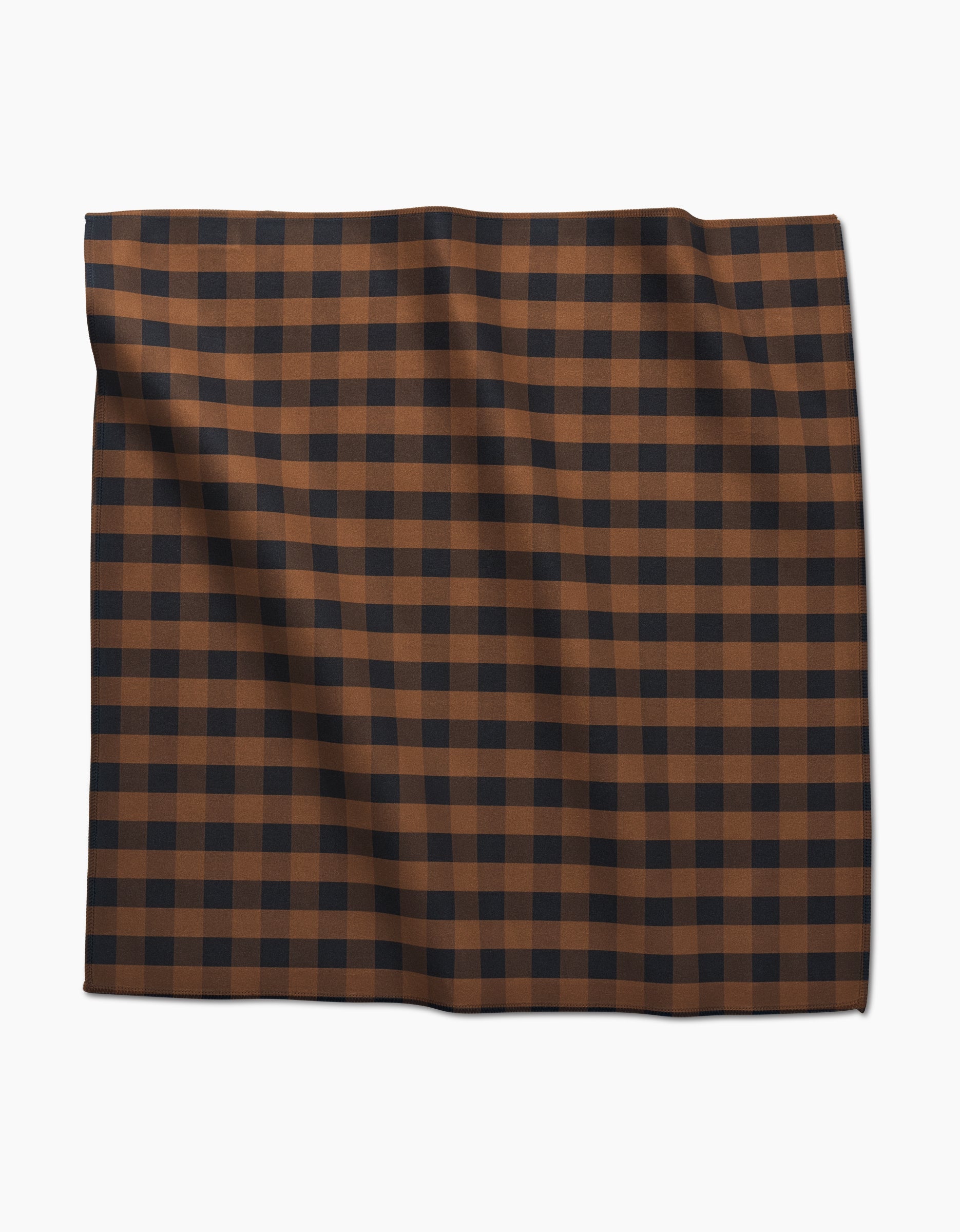 The GEOMETRY Fall Gingham Dinner Napkin features a brown and black checkered grid pattern on soft Geosuede fabric, displayed folded against a white background.