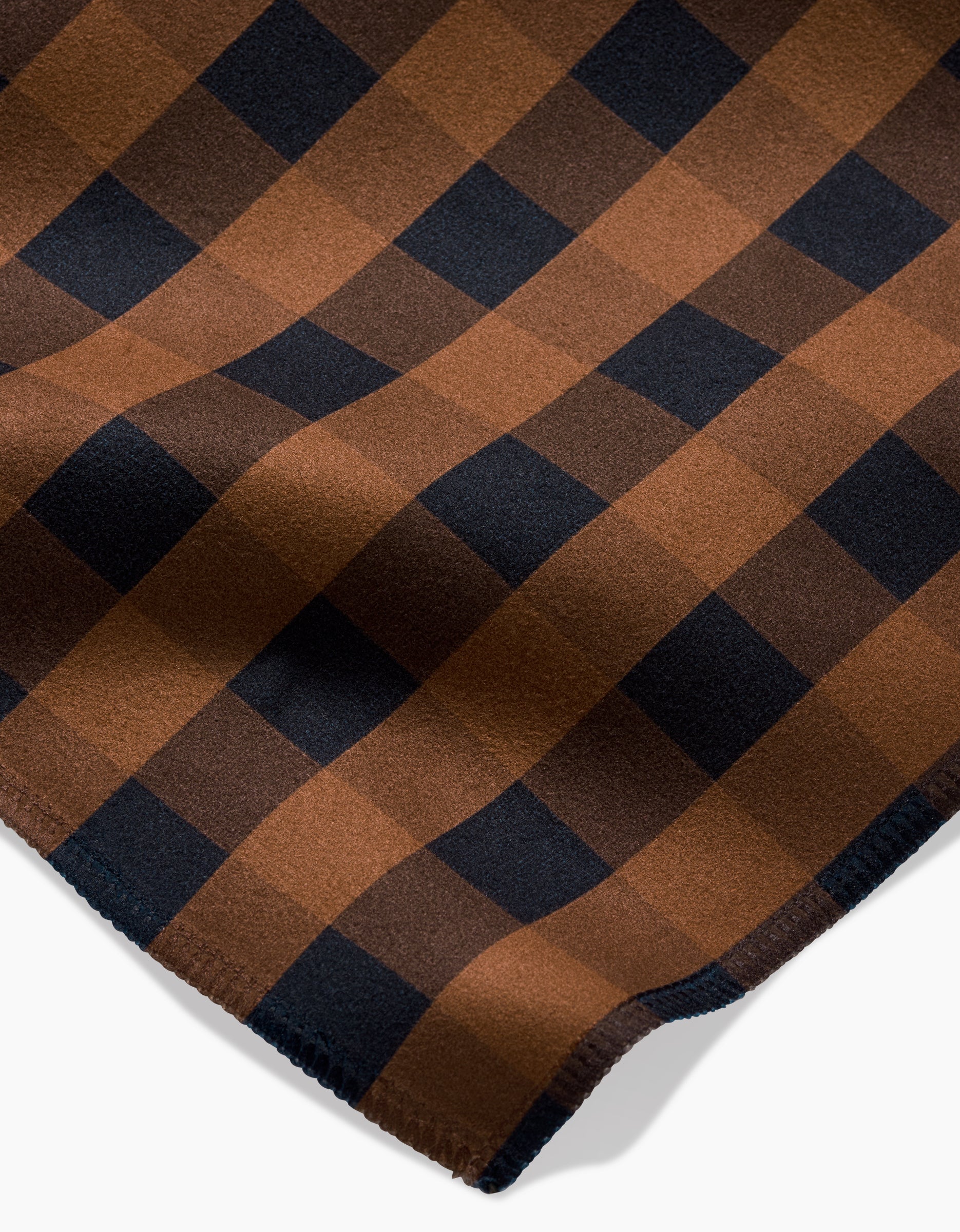 A close-up of Fall Gingham by GEOMETRY, featuring a brown and black checkered pattern on soft Geosuede fabric with neatly stitched edges.