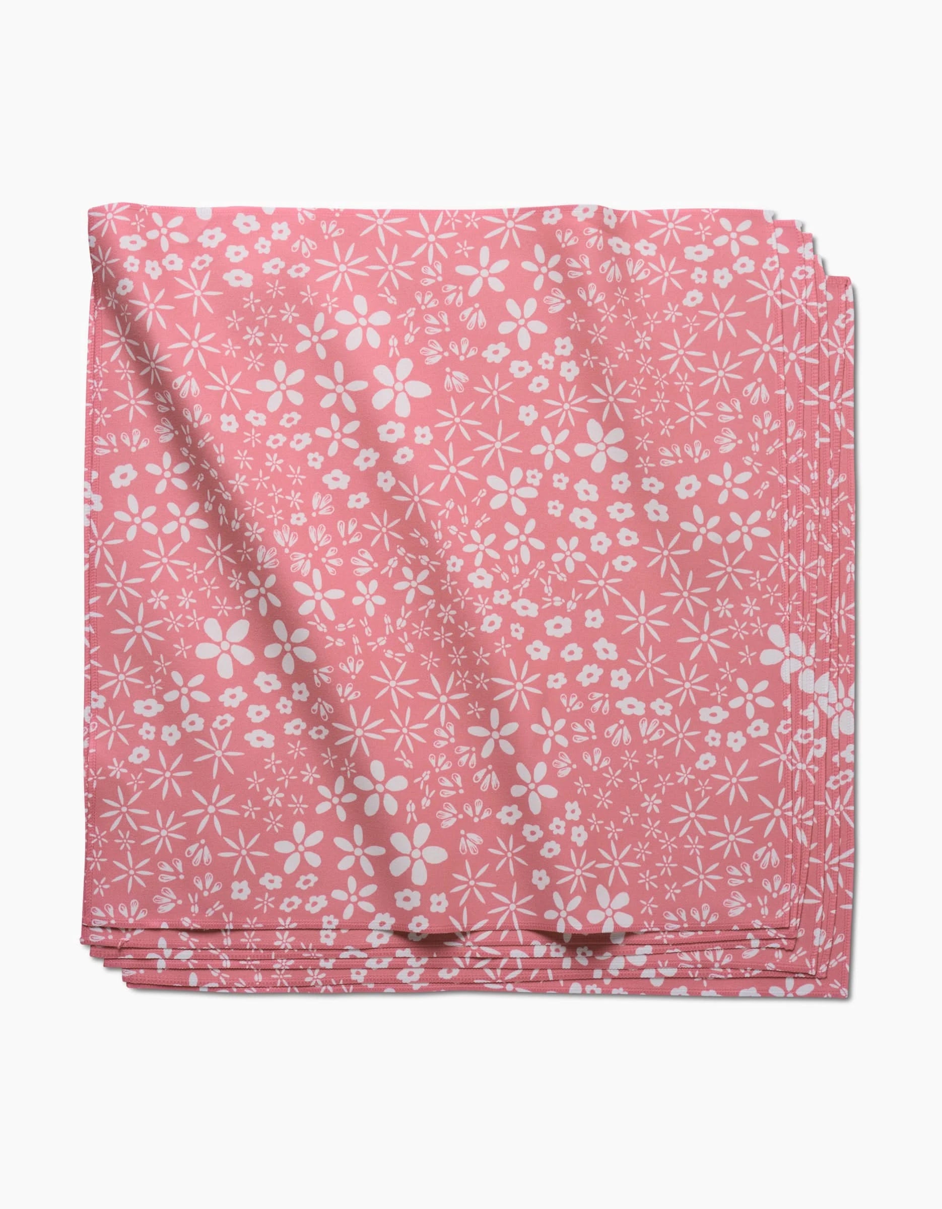 Field of Flowers by Hufton Studio: a folded pink geosuede dinner napkin with a white floral pattern of assorted small flowers, shown on a white background.