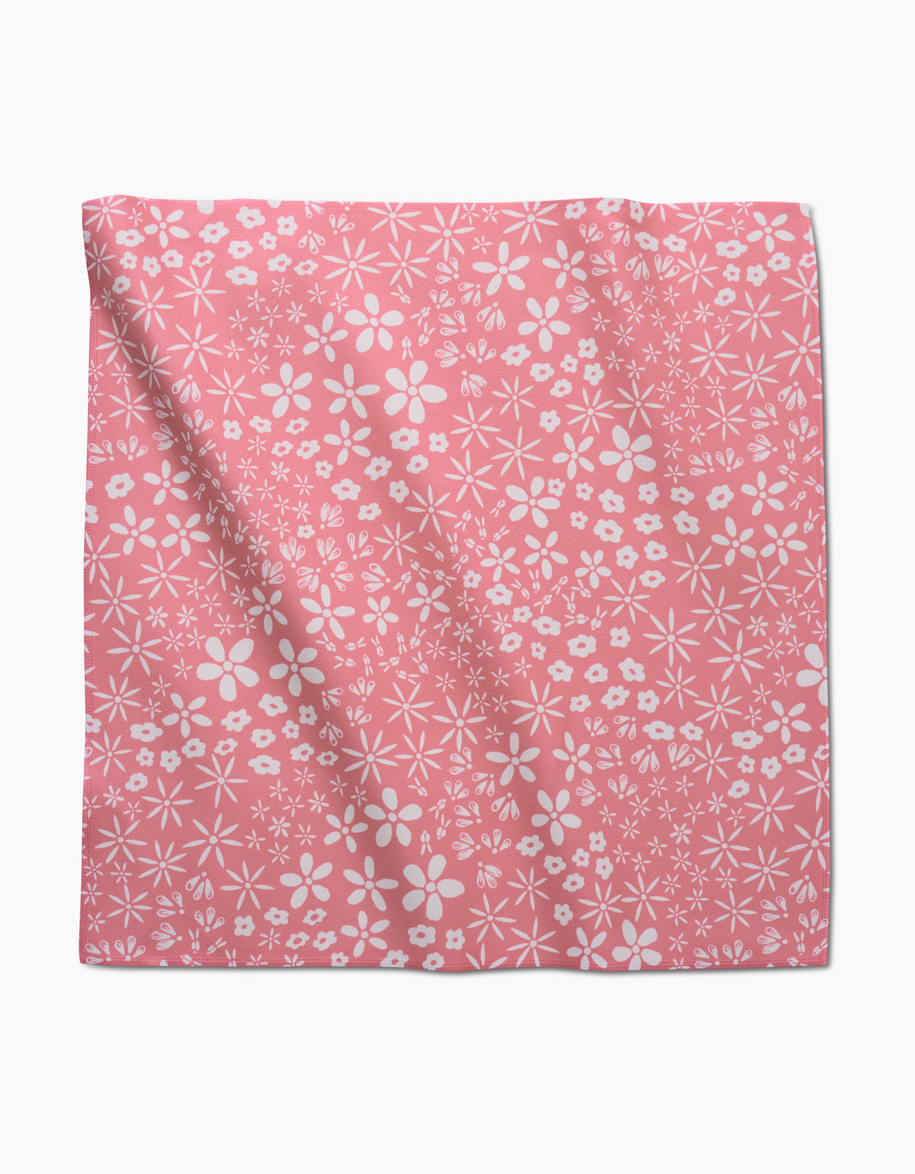 The Field of Flowers dinner napkin by Hufton Studio is crafted from pink Geosuede recycled fabric, featuring a white floral pattern with assorted flowers and subtle folds, laid flat.
