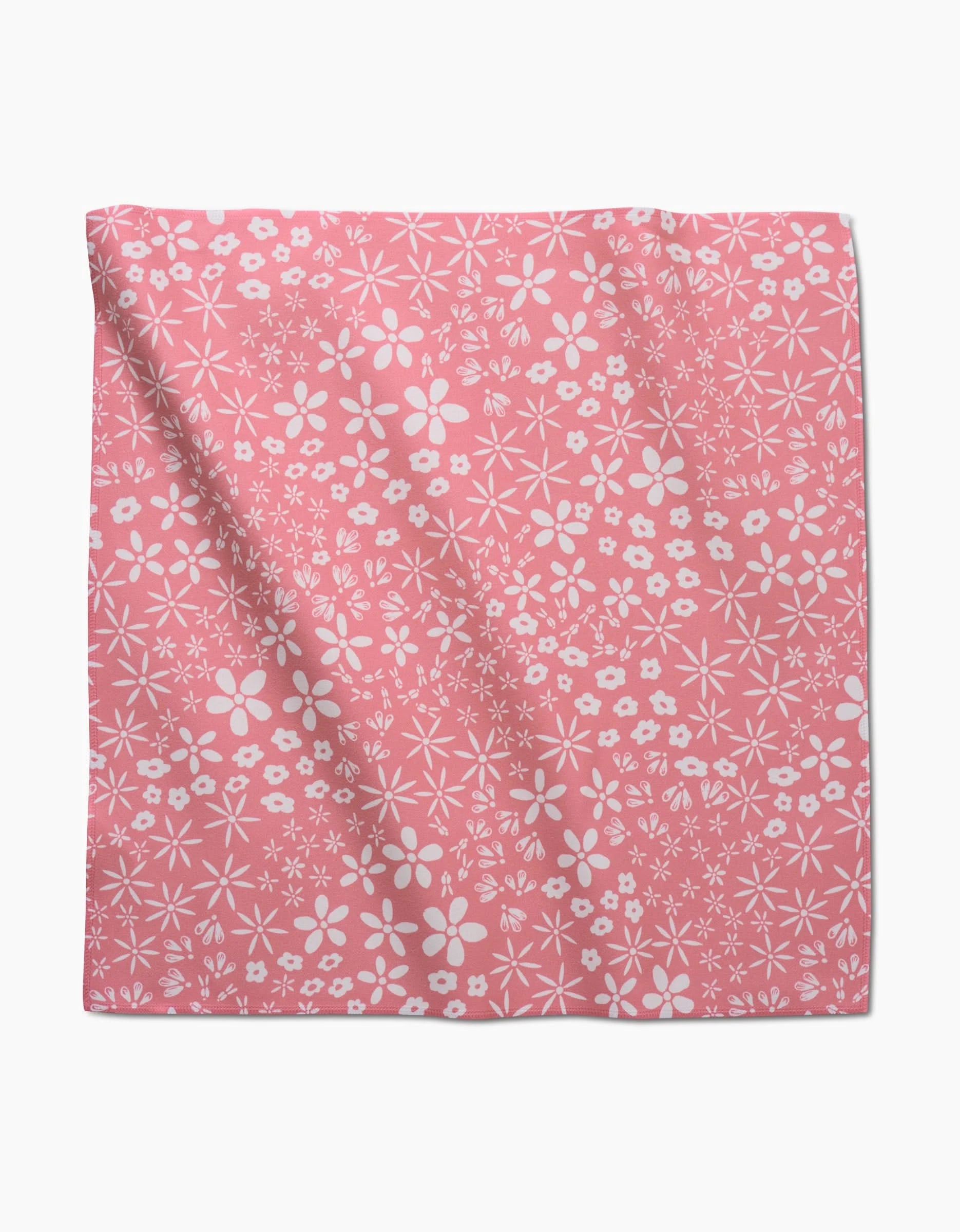 The Field of Flowers dinner napkin by Hufton Studio is crafted from pink Geosuede recycled fabric, featuring a white floral pattern with assorted flowers and subtle folds, laid flat.