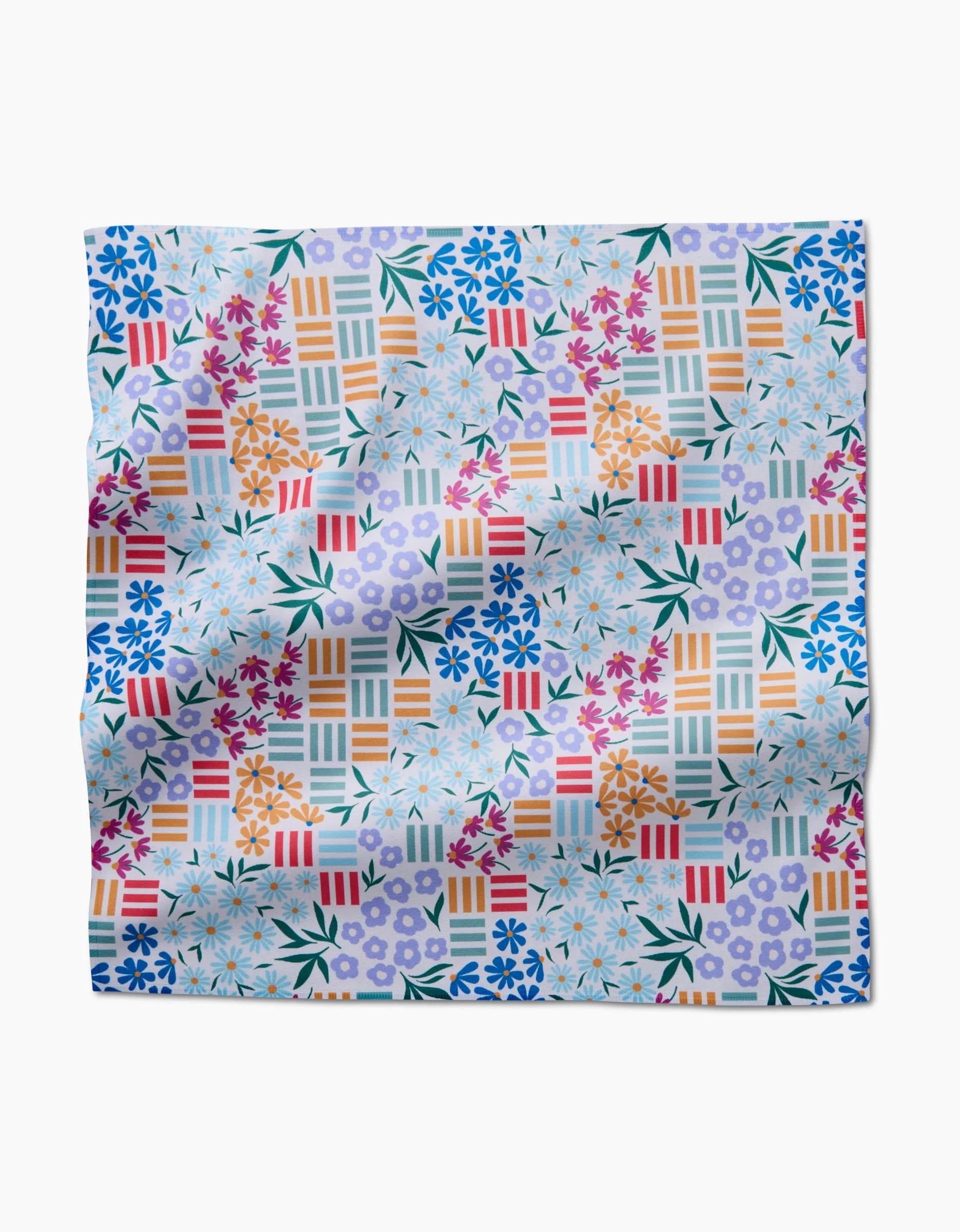 The Floral Garden scarf by Charlie Rowan Designs features blue, purple, and orange flowers with bold geometric stripes on white Geosuede made from recycled materials. Its soft, slightly wrinkled texture highlights sustainable style.
