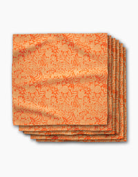 The Florence napkins by Katie OShea are six neatly stacked, eco-friendly orange napkins with a gold floral and vine pattern—stylish dinner décor for any occasion, beautifully displayed against a white background.