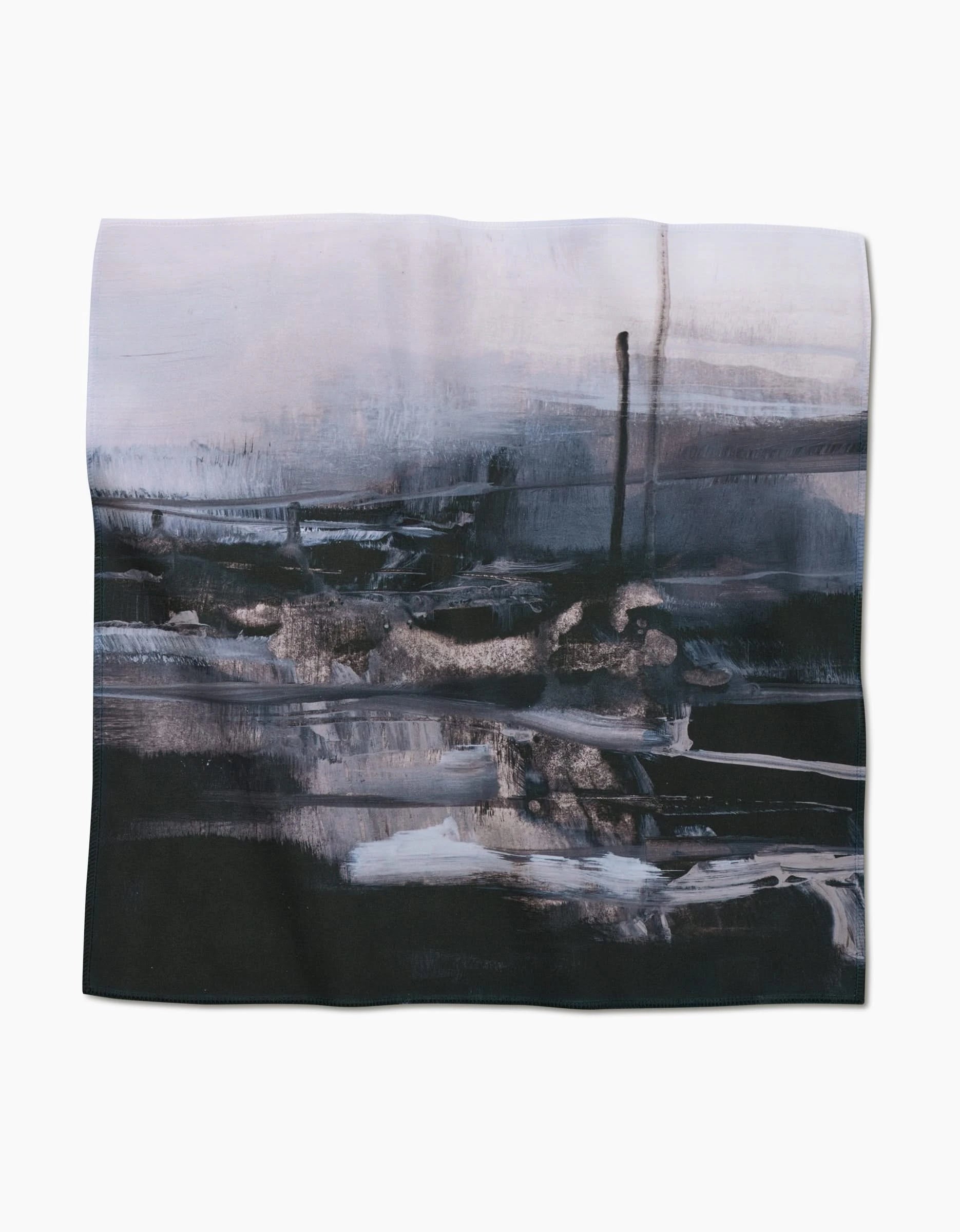 The Icelandic Elements dinner napkin by Jennifer Janesko features an abstract moody landscape with dark blue, black, and white brushstrokes on Geosuede fabric against a light background.