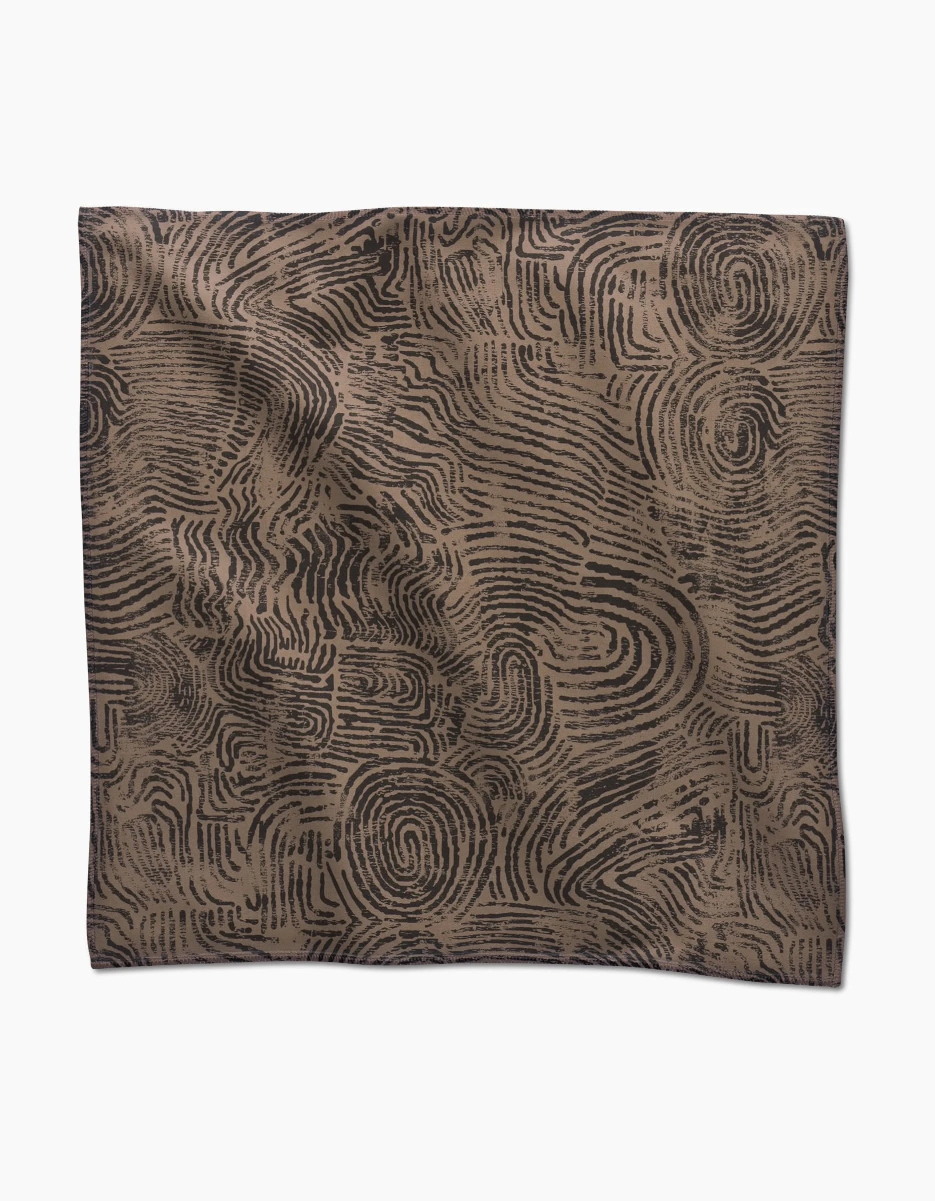 Studio Jeannot’s Imprint is a square dinner napkin set made from recycled Geosuede, featuring a brown base with abstract black fingerprint-like swirls, shown flat on a white background.