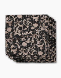 A set of four square recycled dinner napkins by Geometry, named Inverted Floral Black, featuring a beige floral pattern with assorted flowers and leaves on a black background.