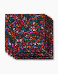 The Rachel Parker Jewel Leaf Swirl dinner napkin features a folded square cloth with vibrant red, orange, pink, purple, and cream leaves swirling on black—an elegant, eco-friendly addition to your napkins collection.