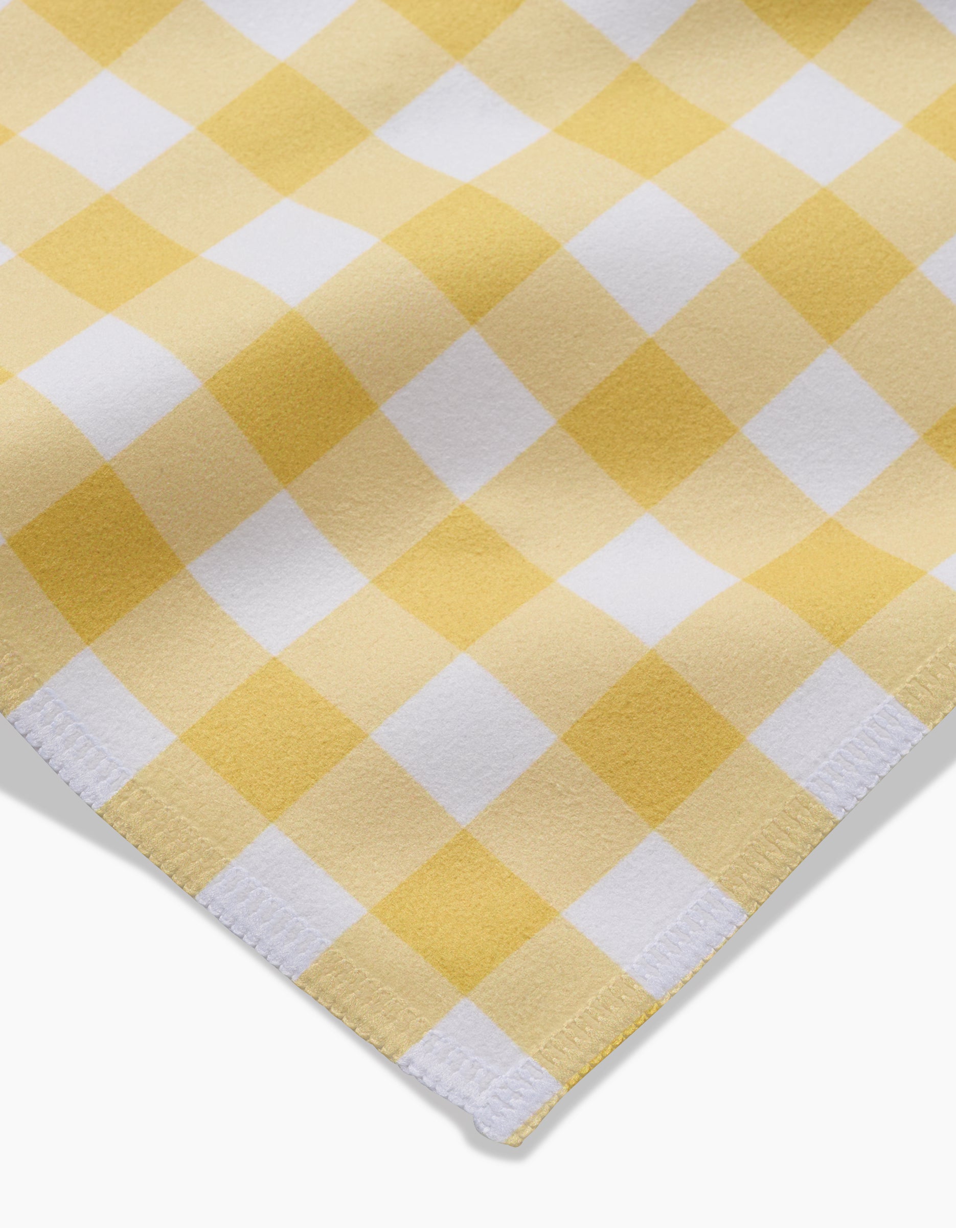 A close-up of the Lemon Gingham Dinner Napkin Set by GEOMETRY, showcasing its yellow and white checkered pattern, stitched edges, and soft Geosuede texture—an eco-friendly choice for your table.