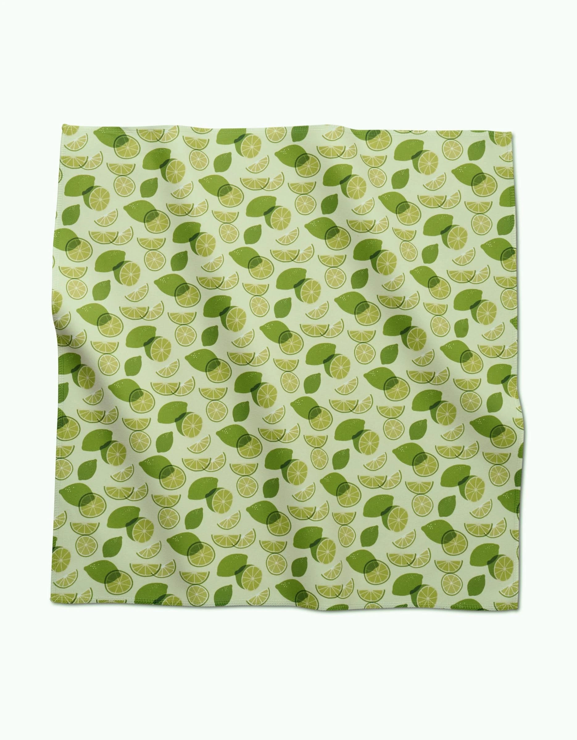 A square GEOMETRY Geosuede fabric piece, named Limes, features a repeating pattern of lime slices and green leaves on a light green background. Made from recycled materials, the fabric appears slightly wrinkled.