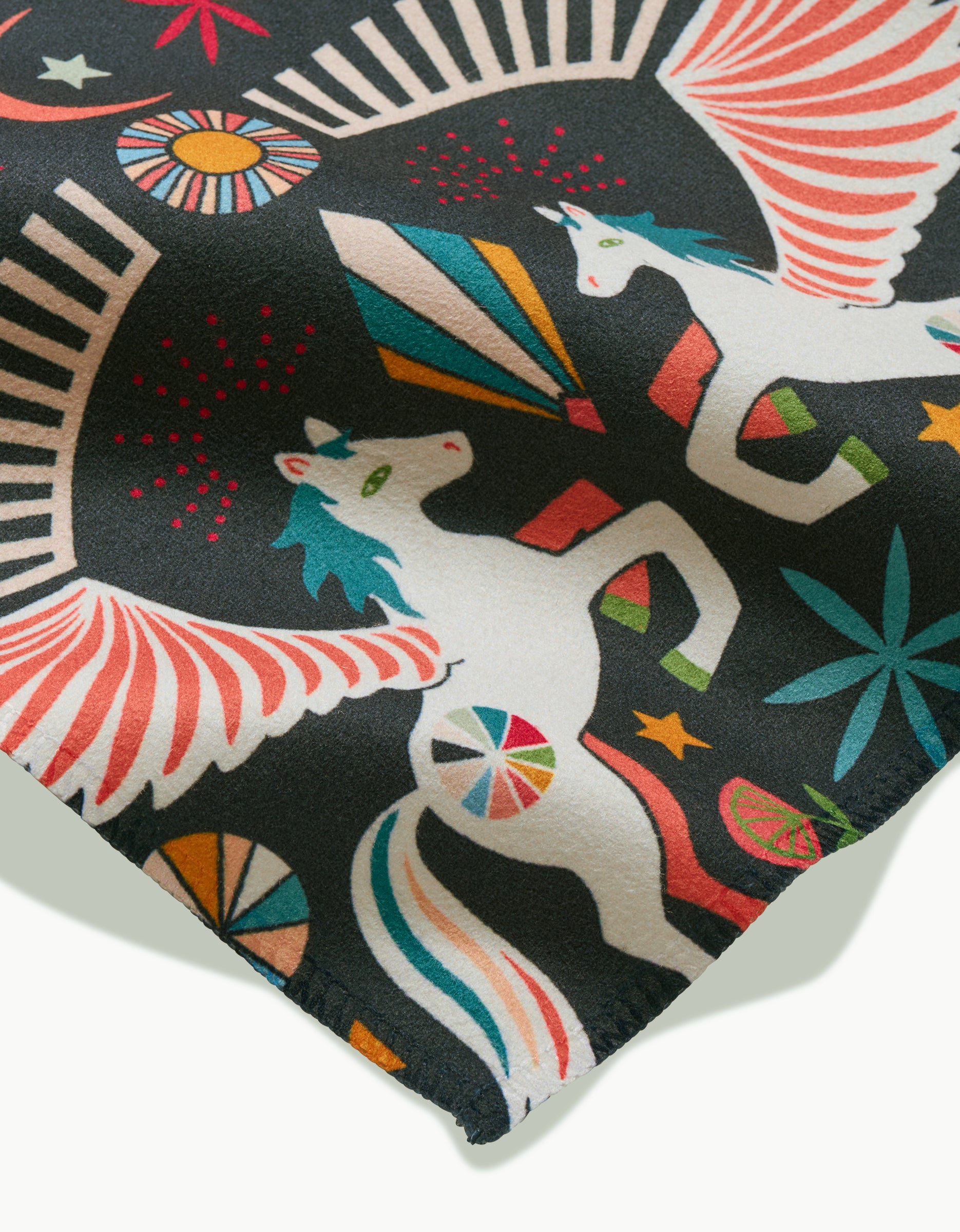 A close-up of Magical Moments fabric by Jessica Swift, featuring white winged unicorns, stars, and geometric shapes in vibrant colors on a dark background—ideal for crafting eco-friendly napkins or a stylish Dinner Napkin Set.