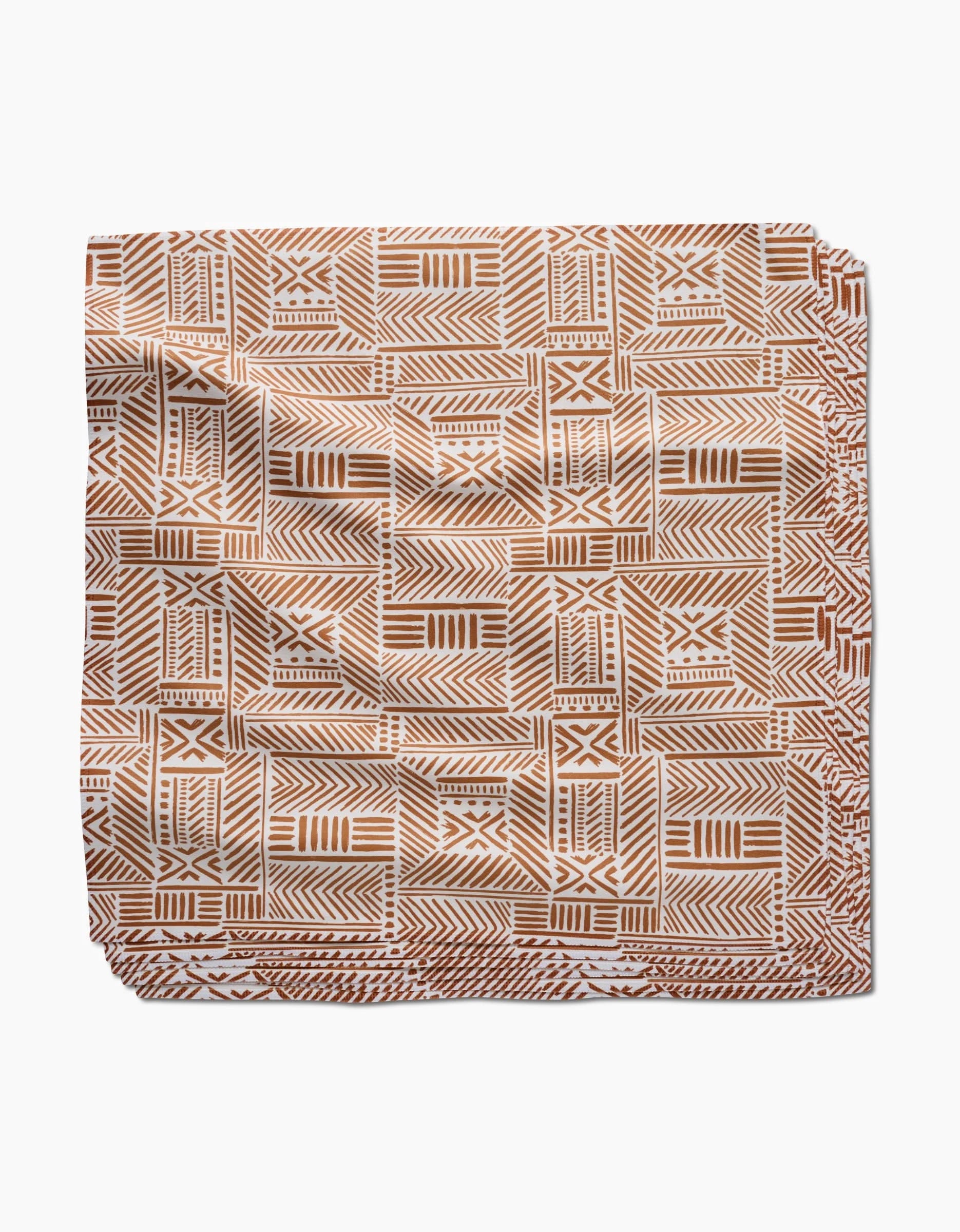 The Mud Cloth Natural Dinner Napkin Set by Hufton Studio features a brown and white geometric pattern with lines, triangles, and squares on soft, eco-friendly Geosuede fabric.