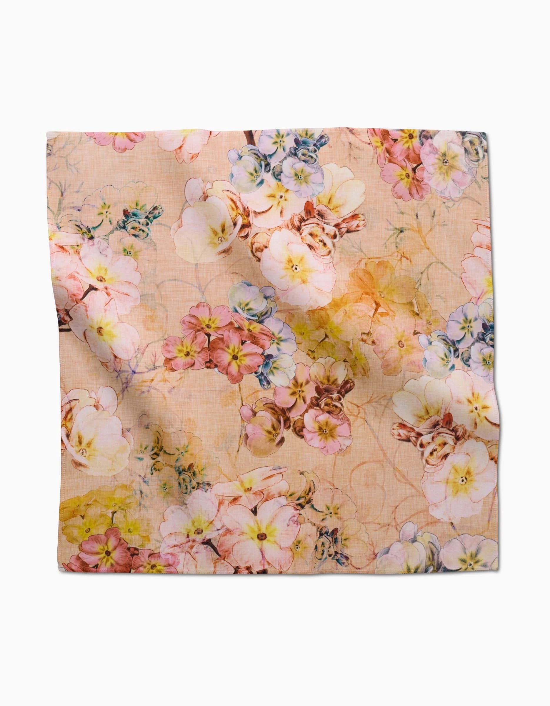 The Primroses square scarf by Pascale Dilger is crafted from eco-friendly Geosuede and features a soft peach base with a dense, elegant floral pattern in pink, yellow, white, blue, and green—ideal as a dinner napkin or accessory.