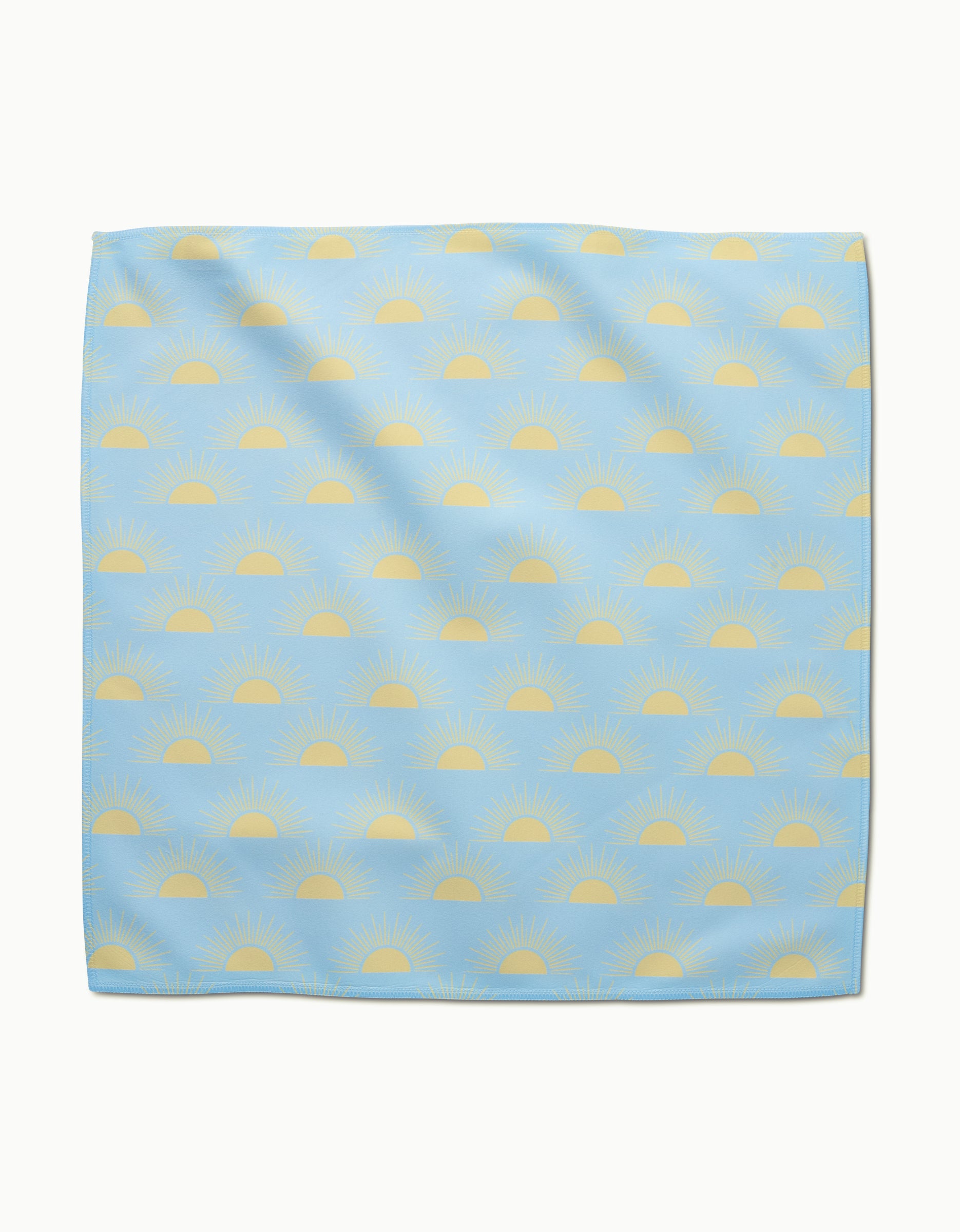 The GEOMETRY Soft Summer Sun dinner napkin features light blue Geosuede fabric with yellow sunrise patterns in horizontal rows, crafted from recycled materials for a sustainable touch.