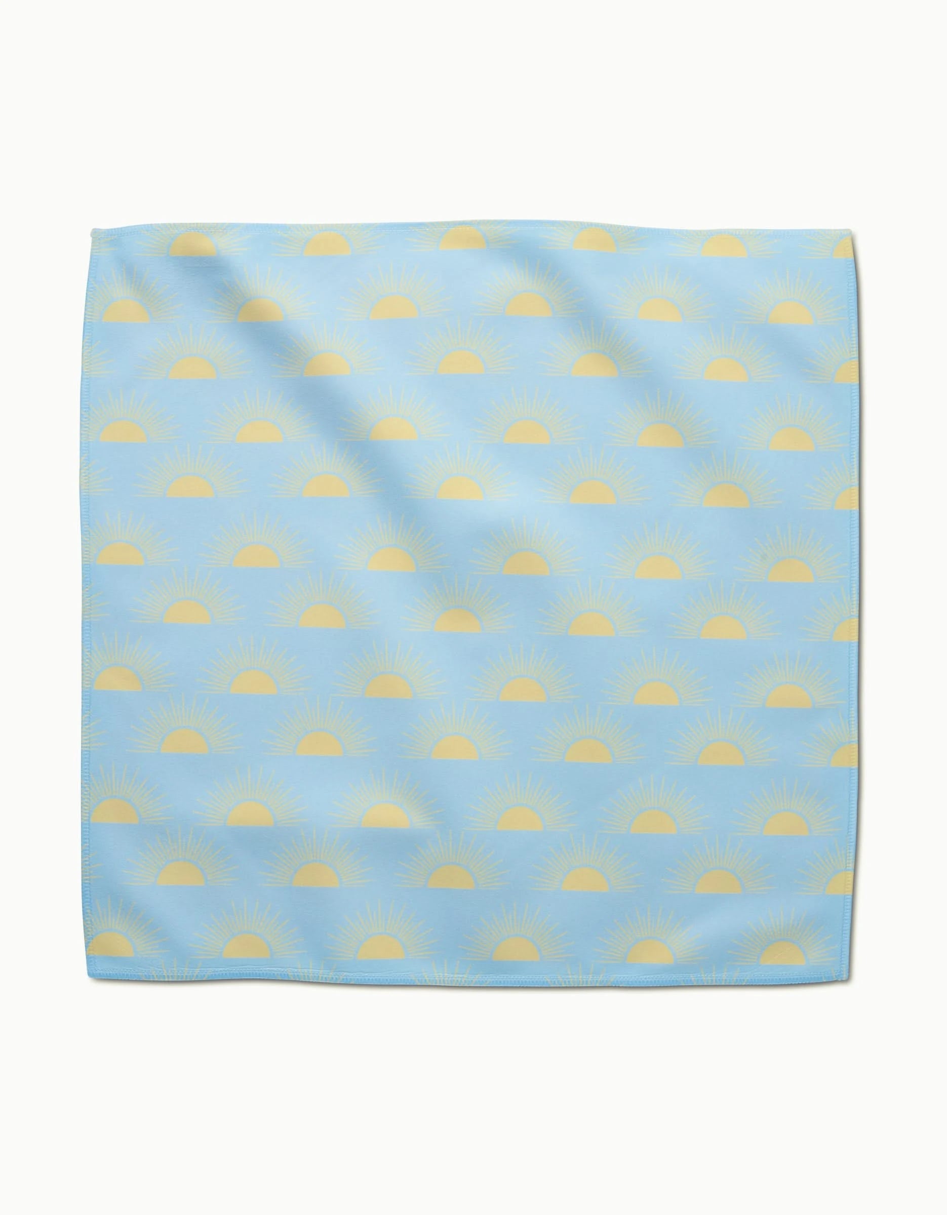 The GEOMETRY Soft Summer Sun dinner napkin features light blue Geosuede fabric with yellow sunrise patterns in horizontal rows, crafted from recycled materials for a sustainable touch.